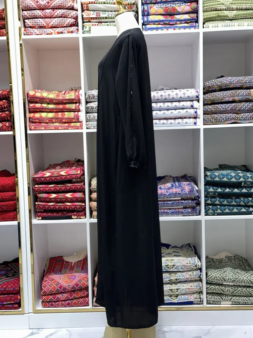 Black abaya simple design by Palestinian Elegance displayed on mannequin in fabric store