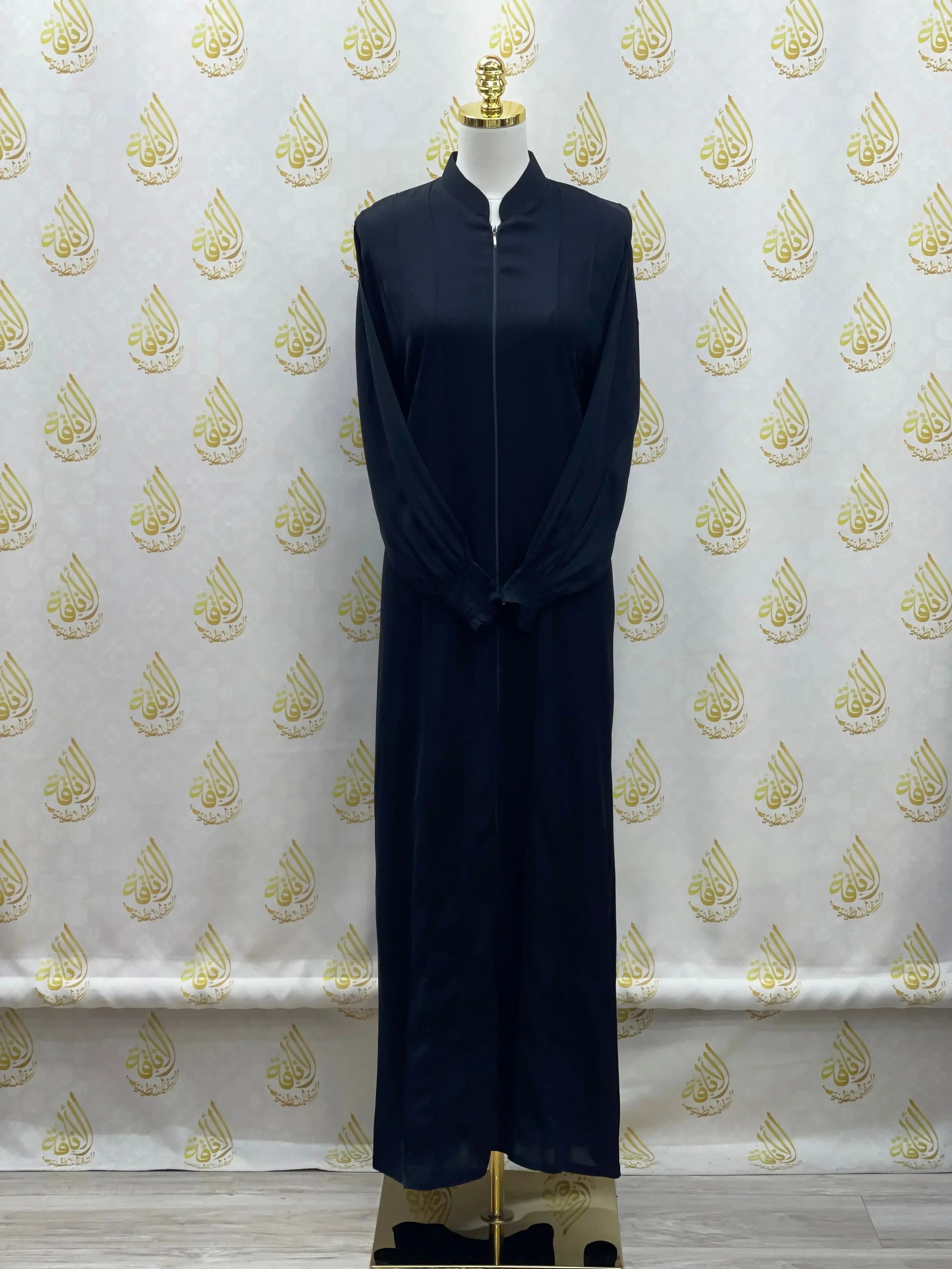 Palestinian Elegance black abaya with embroidery displayed on mannequin against patterned backdrop