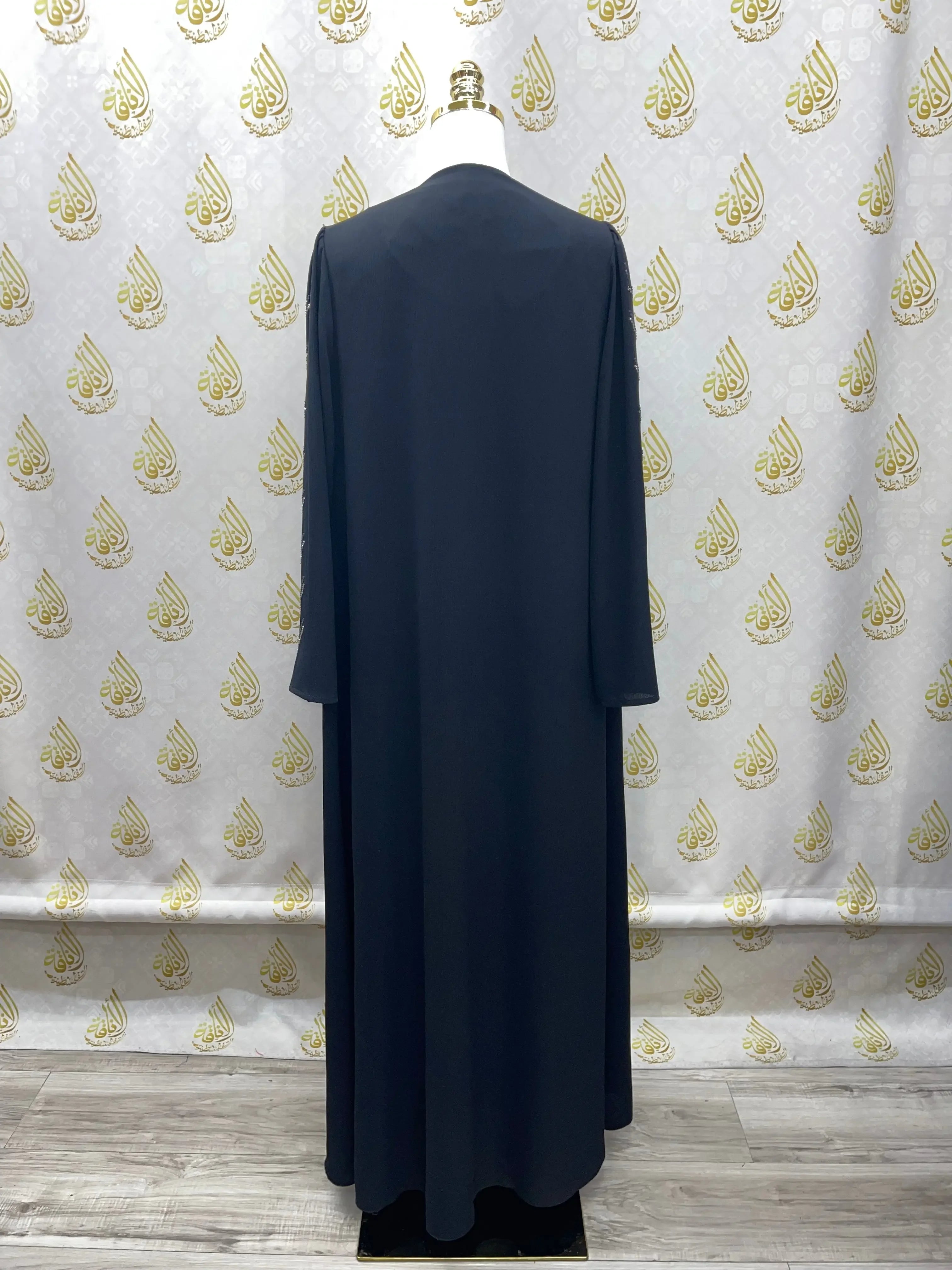 Black Abaya with Strass from Palestinian Elegance displayed on mannequin against patterned backdrop