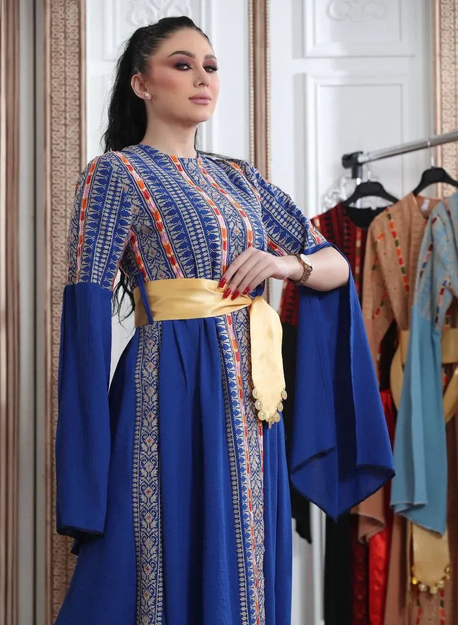 Palestinian Elegance embroidered Manjel dress in blue with intricate patterns and yellow sash belt
