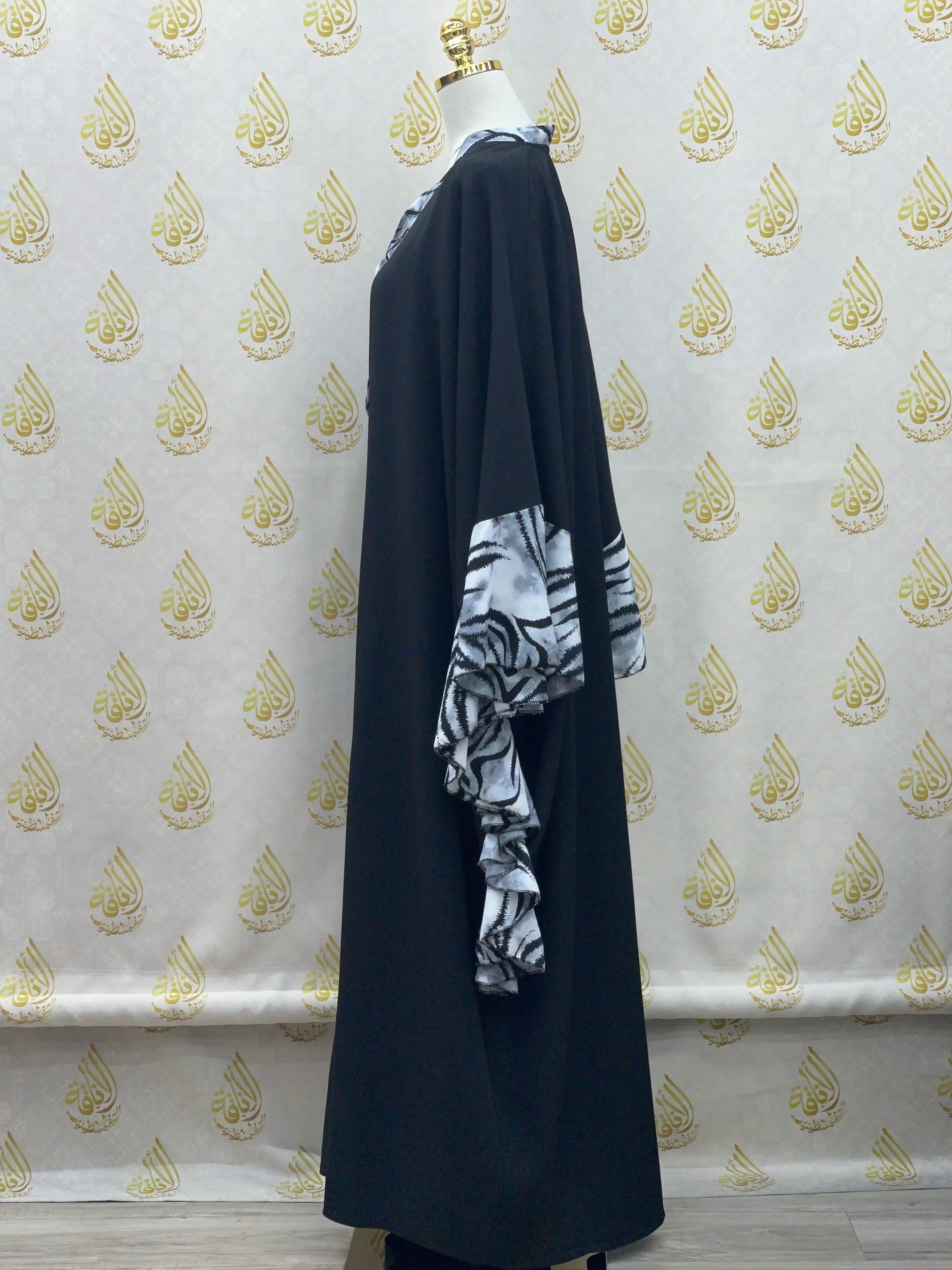 Palestinian Elegance black butterfly abaya dress with white patterned ruffle sleeves displayed on mannequin