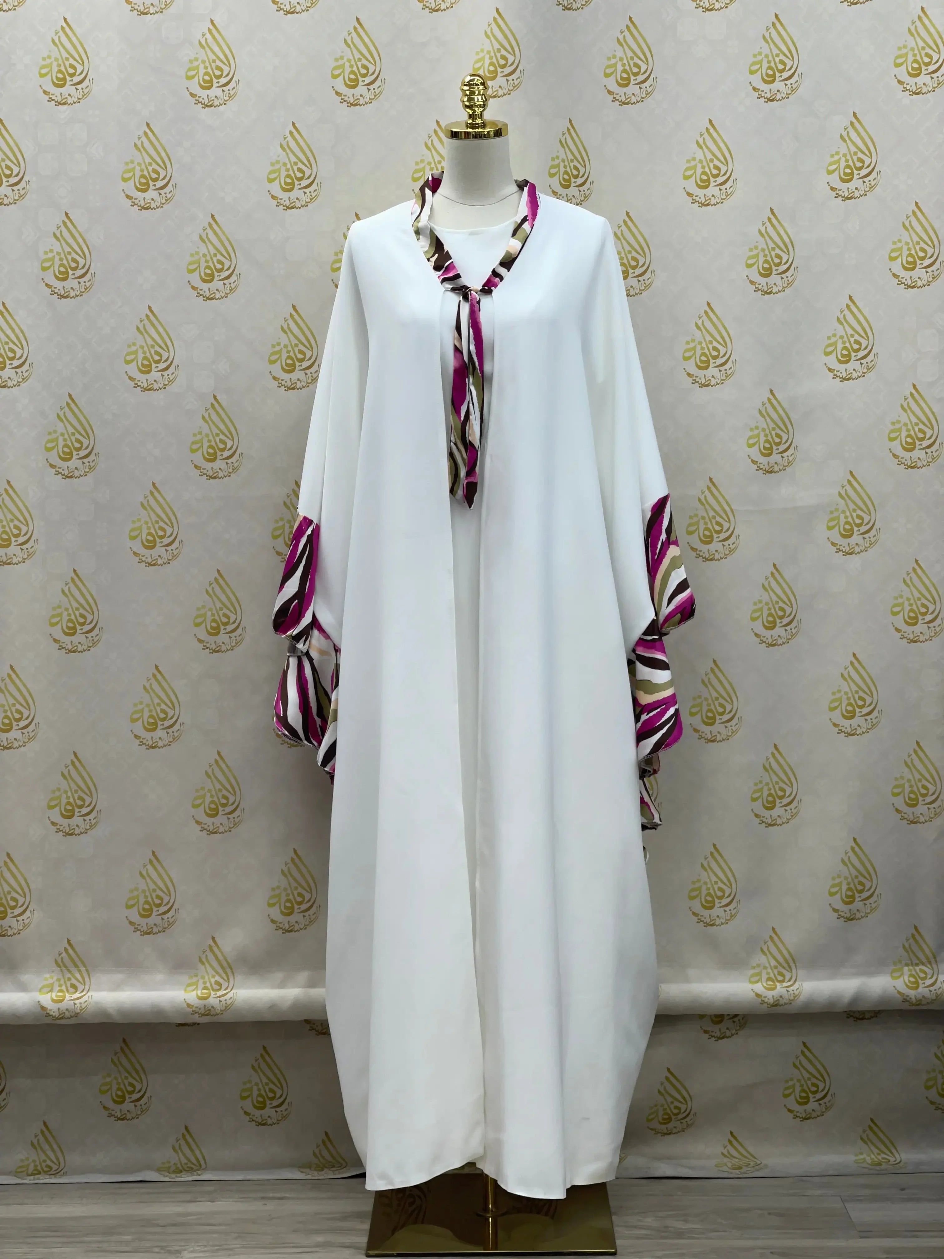 White butterfly abaya dress by Palestinian Elegance with pink and purple patterned trim on sleeves and neckline