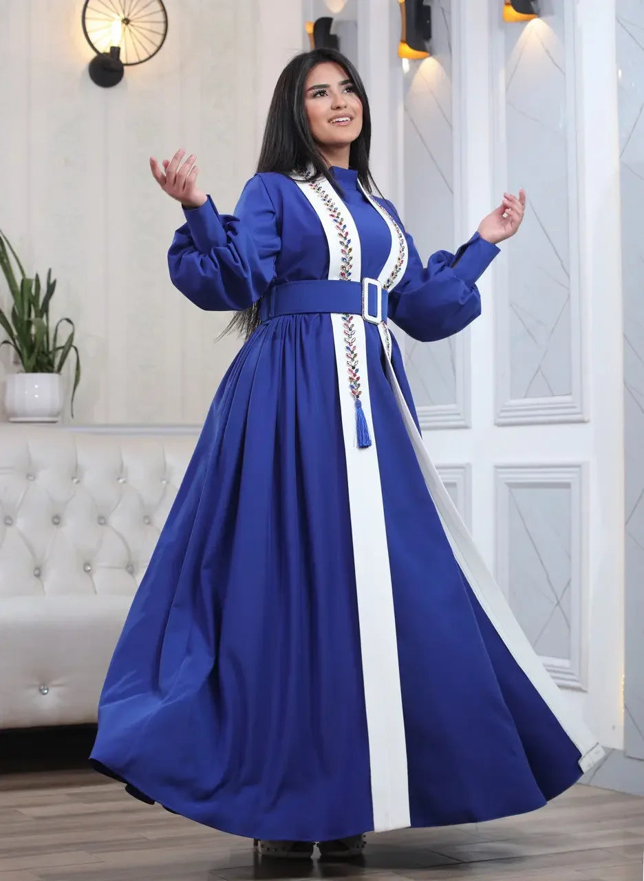 Palestinian Elegance blue crystal kaftan dress with white accents and a belted waist worn by a smiling woman