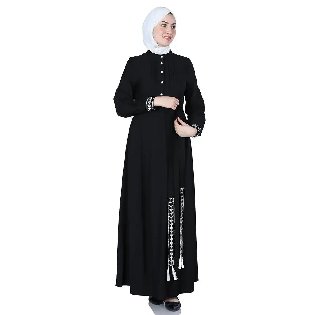 Palestinian Elegance black modest dress with embroidered cuffs and tassels styled on model wearing white hijab