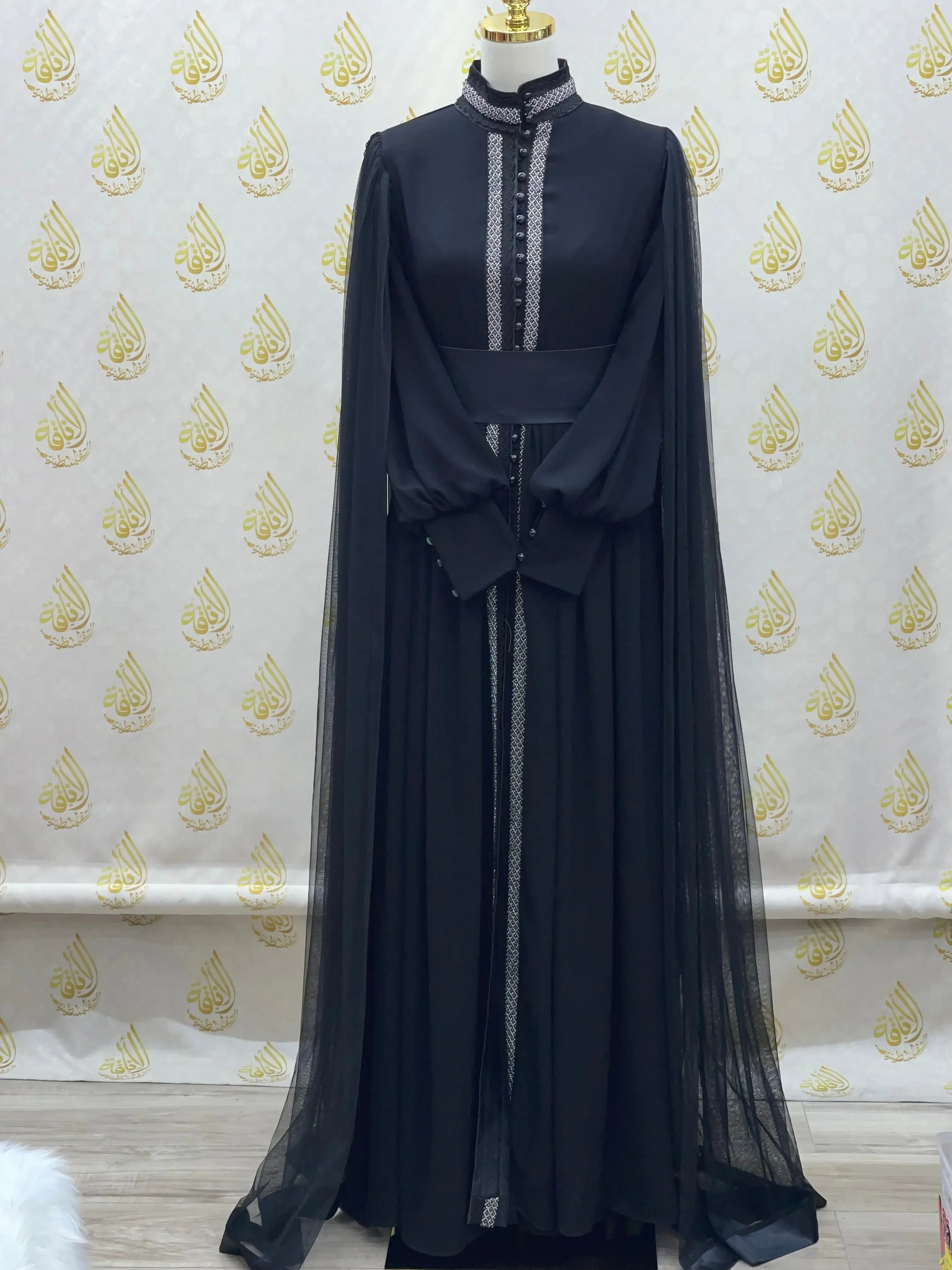 Elegant modest formal dress by Palestinian Elegance in black with sheer long sleeves and decorative front details