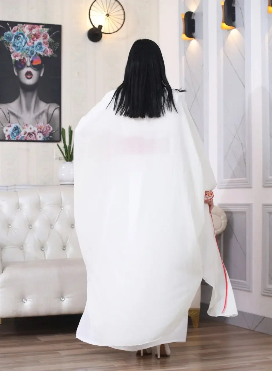 Back view of embroidered abaya with cardigan in white by Palestinian Elegance worn by a woman indoors