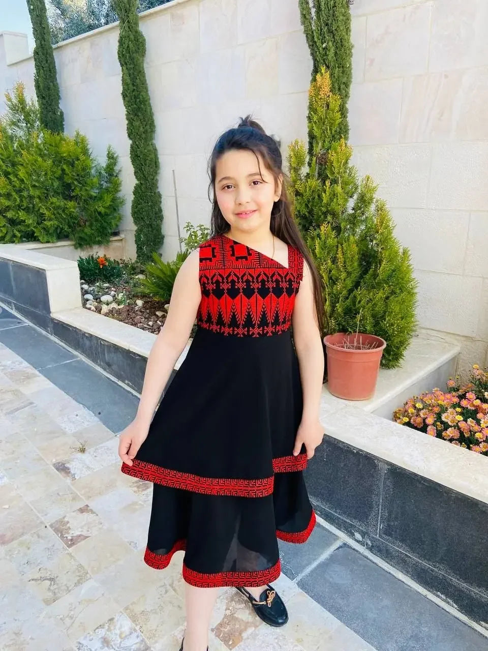 Palestinian Elegance embroidered dress for kids featuring black fabric with red traditional embroidery