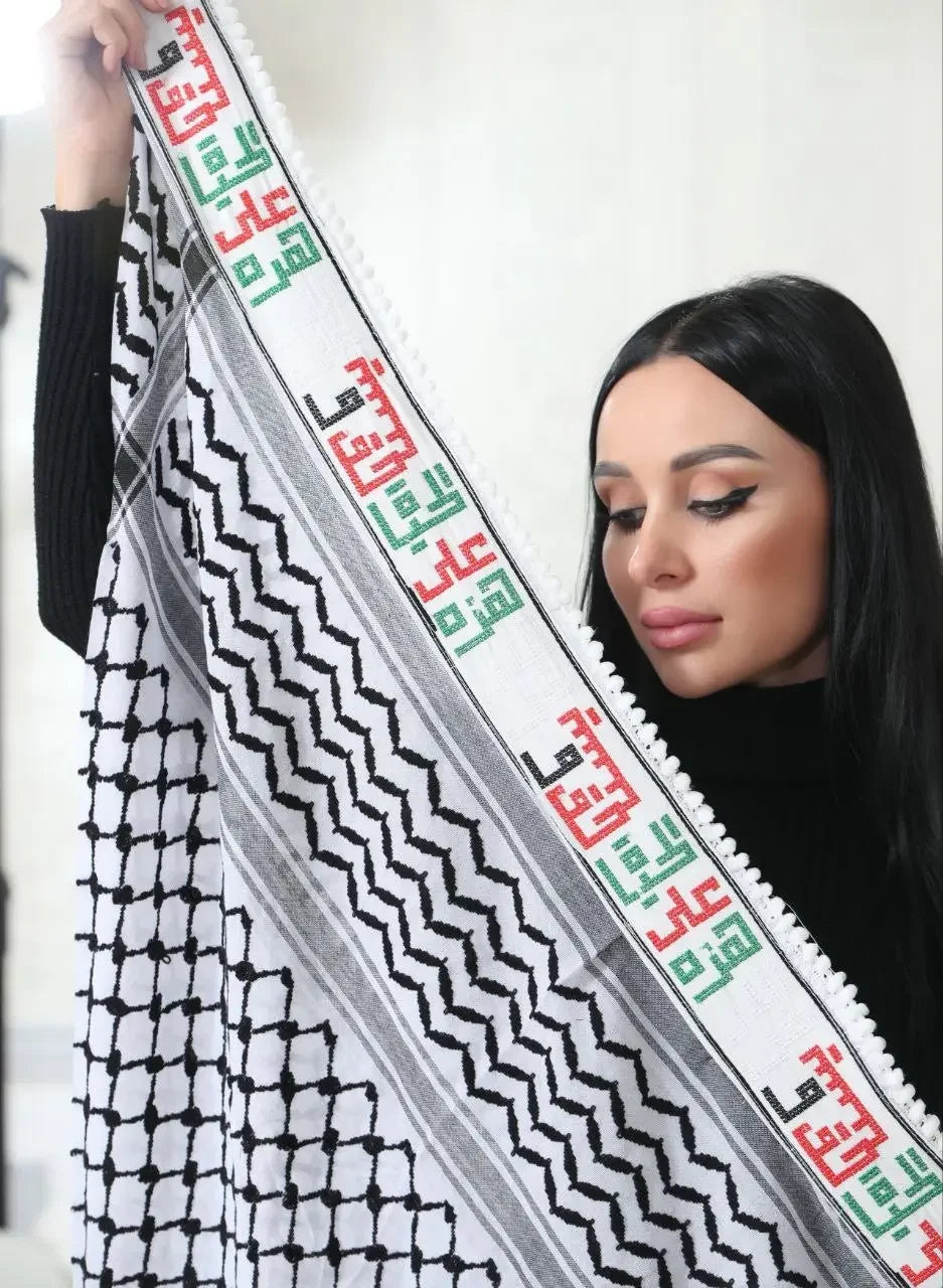 Woman holding an embroidered kuffiyeh scarf with traditional black and white patterns and colorful embroidery