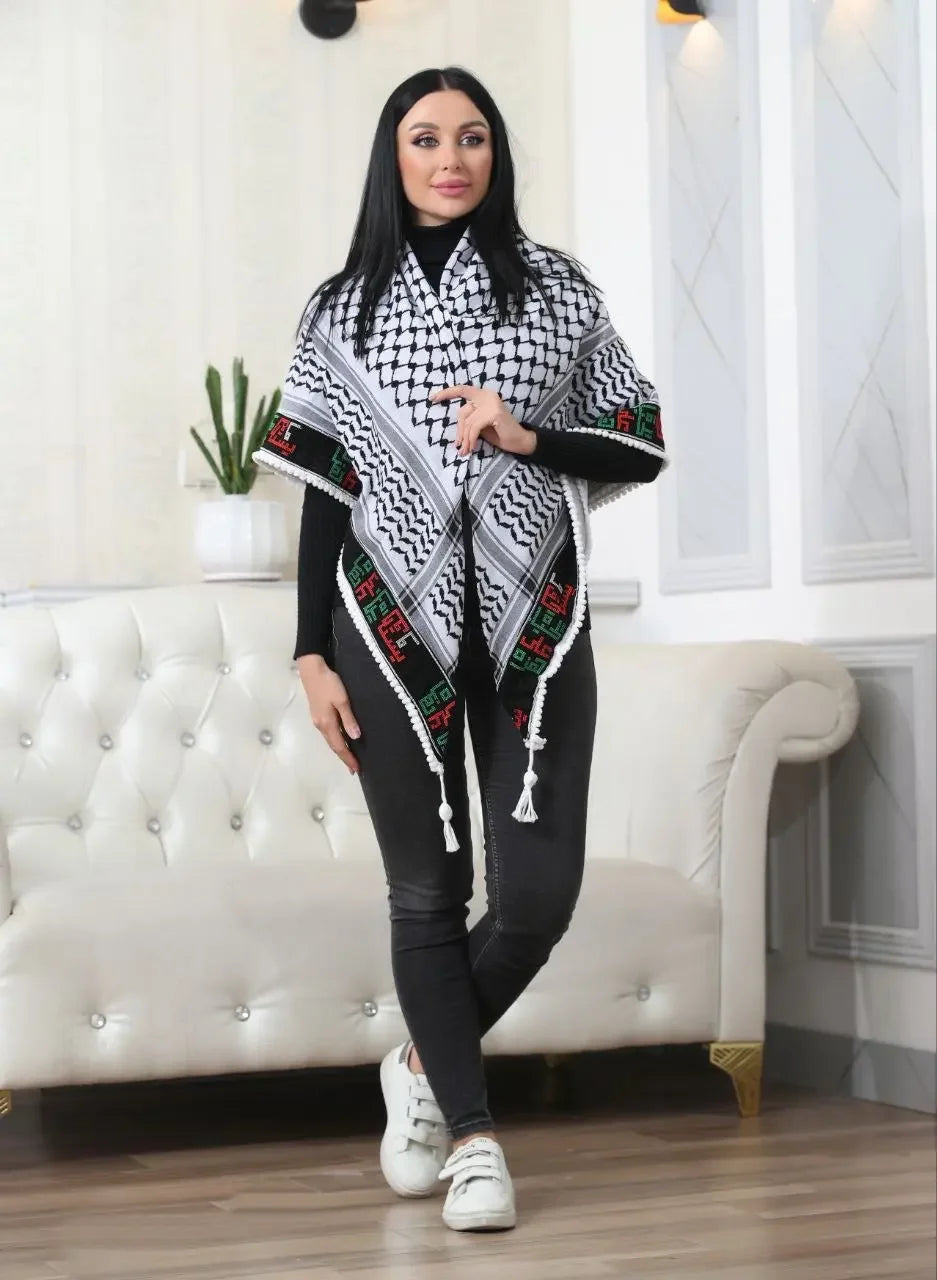 Woman wearing Palestinian Elegance embroidered kuffiyeh scarf styled over black outfit in modern living room
