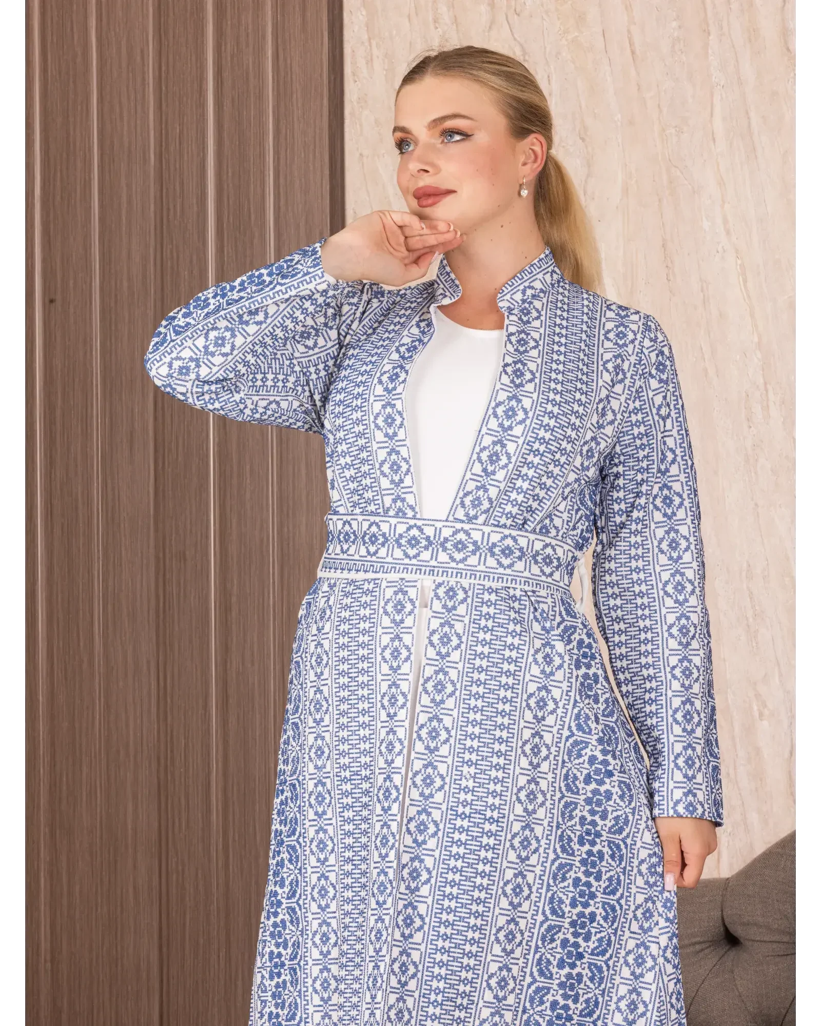 Palestinian Elegance embroidered long cardigan with intricate blue and white geometric patterns on a woman