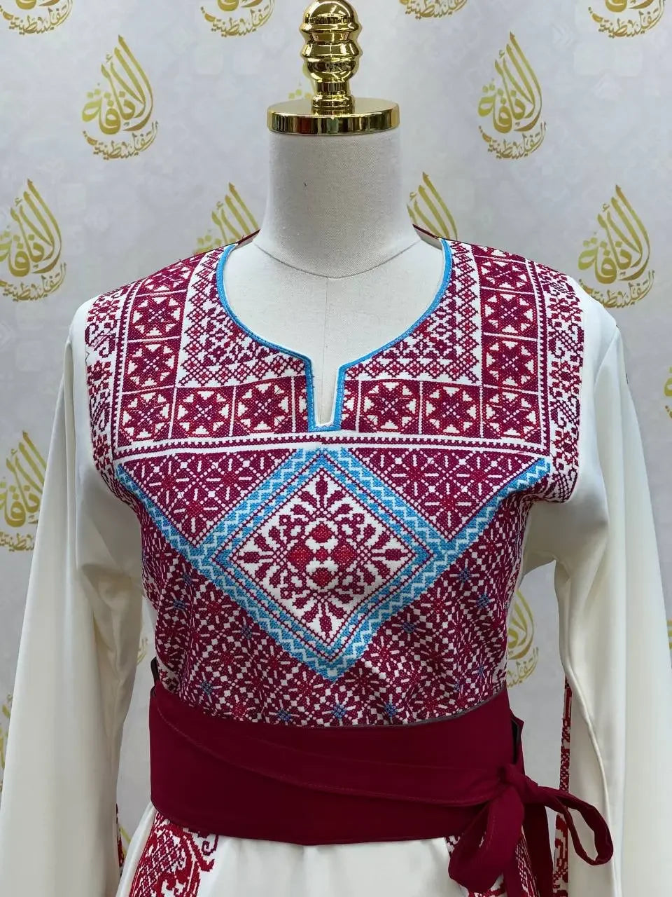 Palestinian Elegance embroidered modest fashion dress with traditional red and blue embroidery on white fabric
