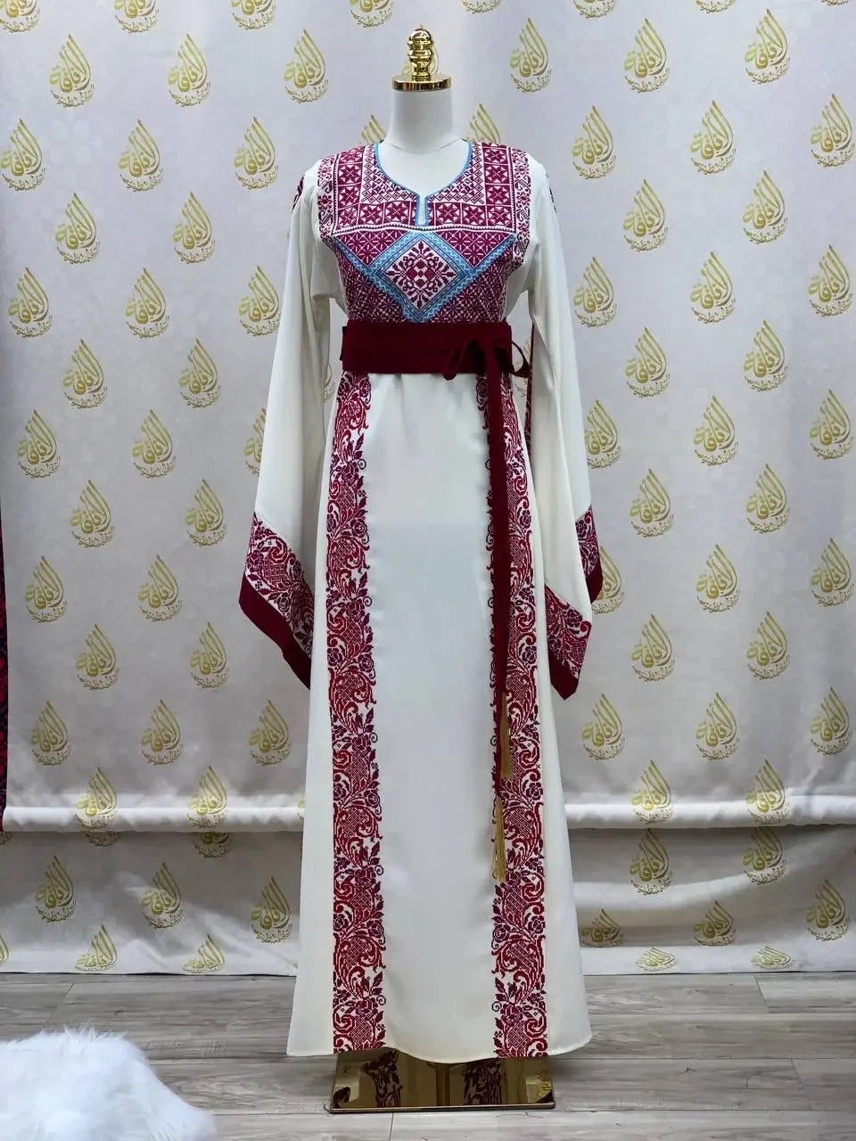 Palestinian Elegance embroidered modest fashion dress in white with detailed red and blue embroidery and a matching sash