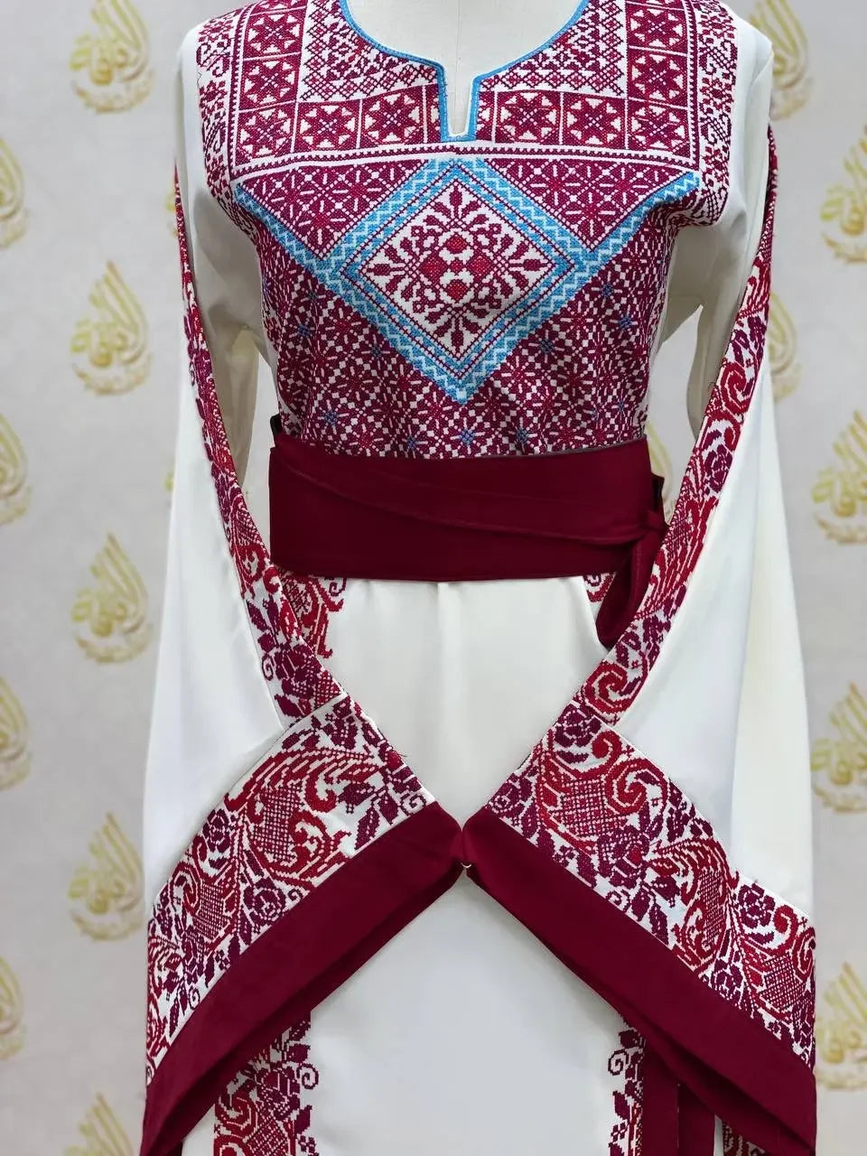 Palestinian Elegance embroidered modest fashion dress with detailed red and blue embroidery on white fabric