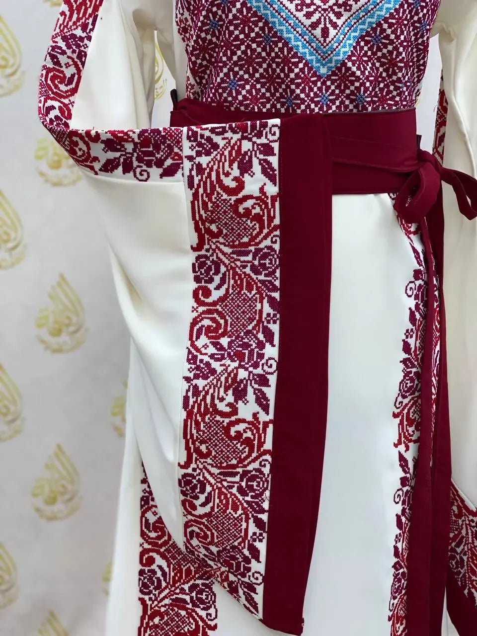 White embroidered modest fashion dress with intricate red and blue Palestinian Elegance embroidery details