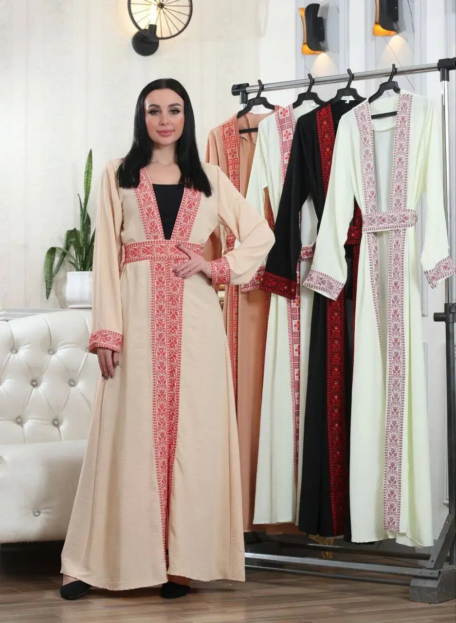 Palestinian Elegance embroidered open cardigan in beige with traditional red embroidery worn by a woman with more cardigans on a rack