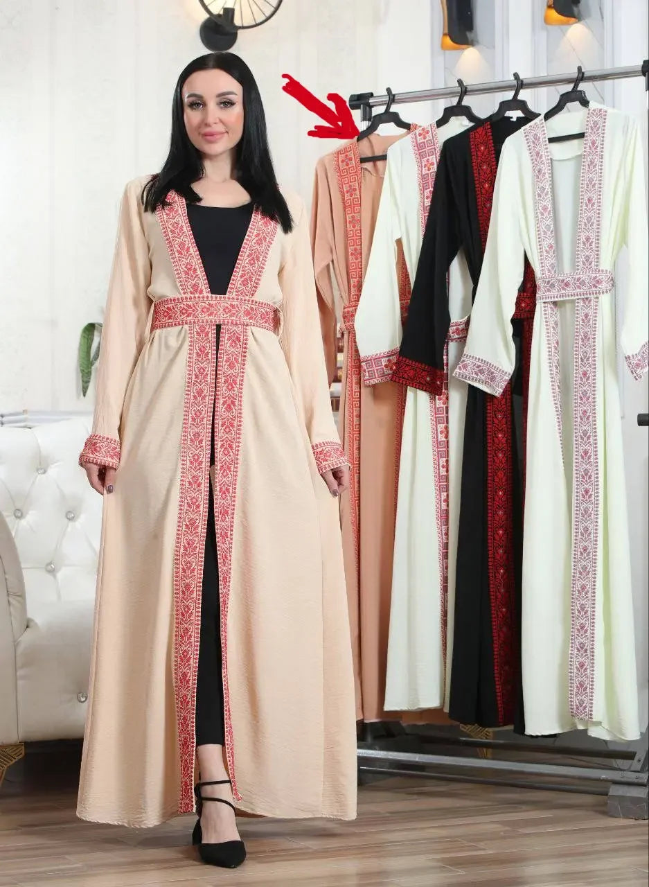 Palestinian Elegance embroidered open cardigan in beige with traditional red patterns worn by woman with rack showing multiple colors