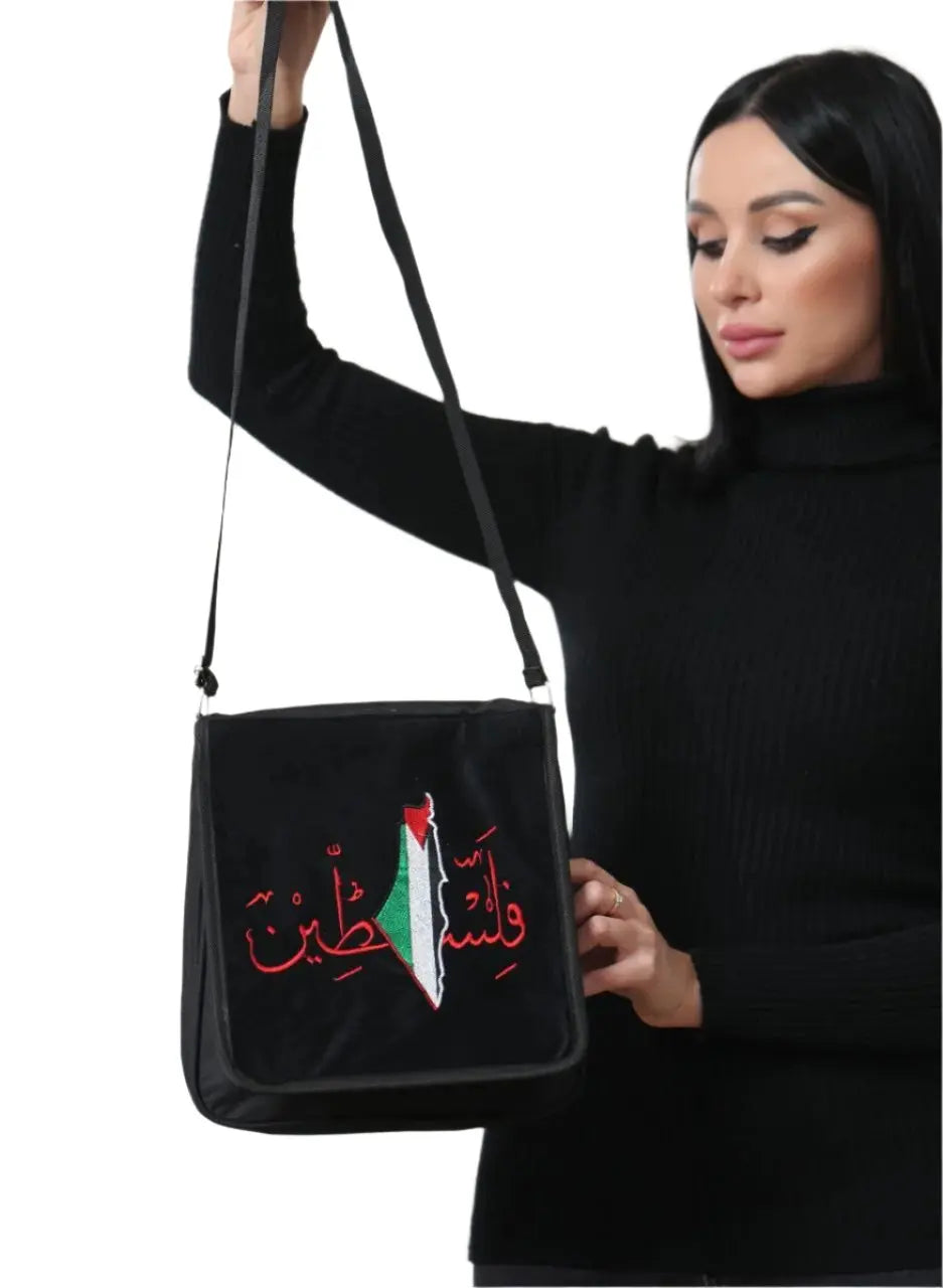 Black embroidered Palestine shoulder bag with red Arabic calligraphy and map detail held by woman