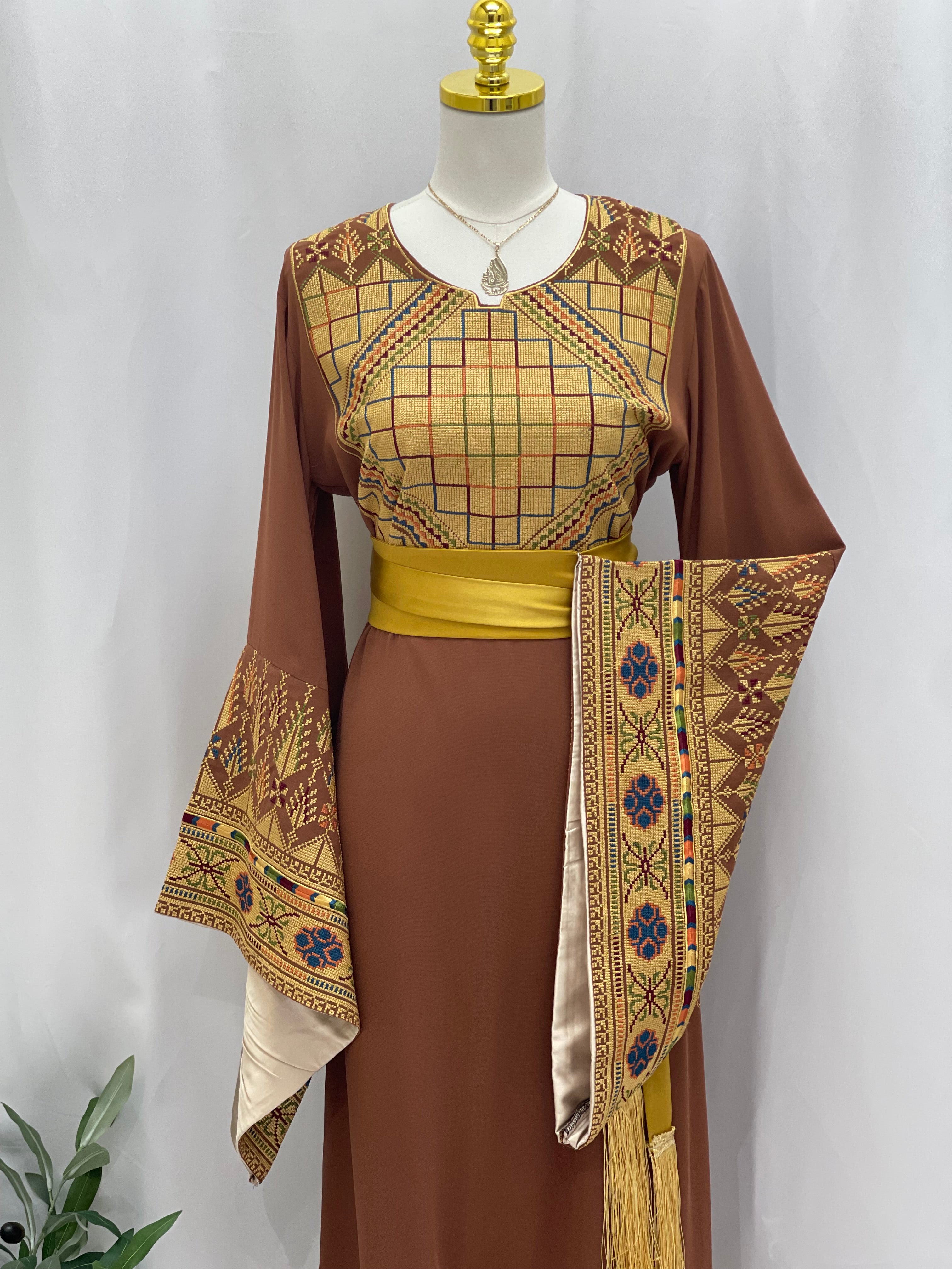 Embroidered Palestinian thoub dress in brown with intricate traditional patterns and a yellow sash