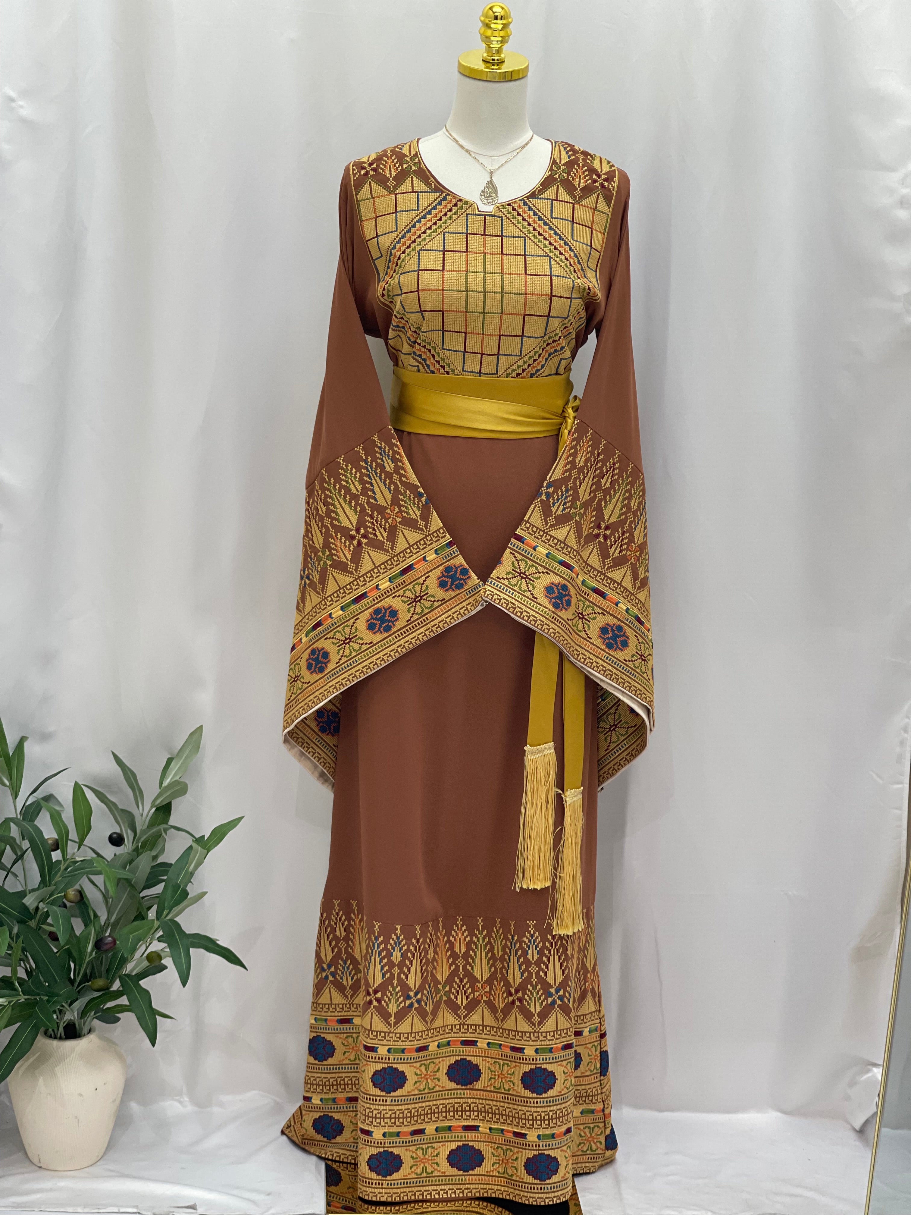 Embroidered Palestinian thoub dress by Palestinian Elegance in brown with intricate gold and blue embroidery and yellow sash