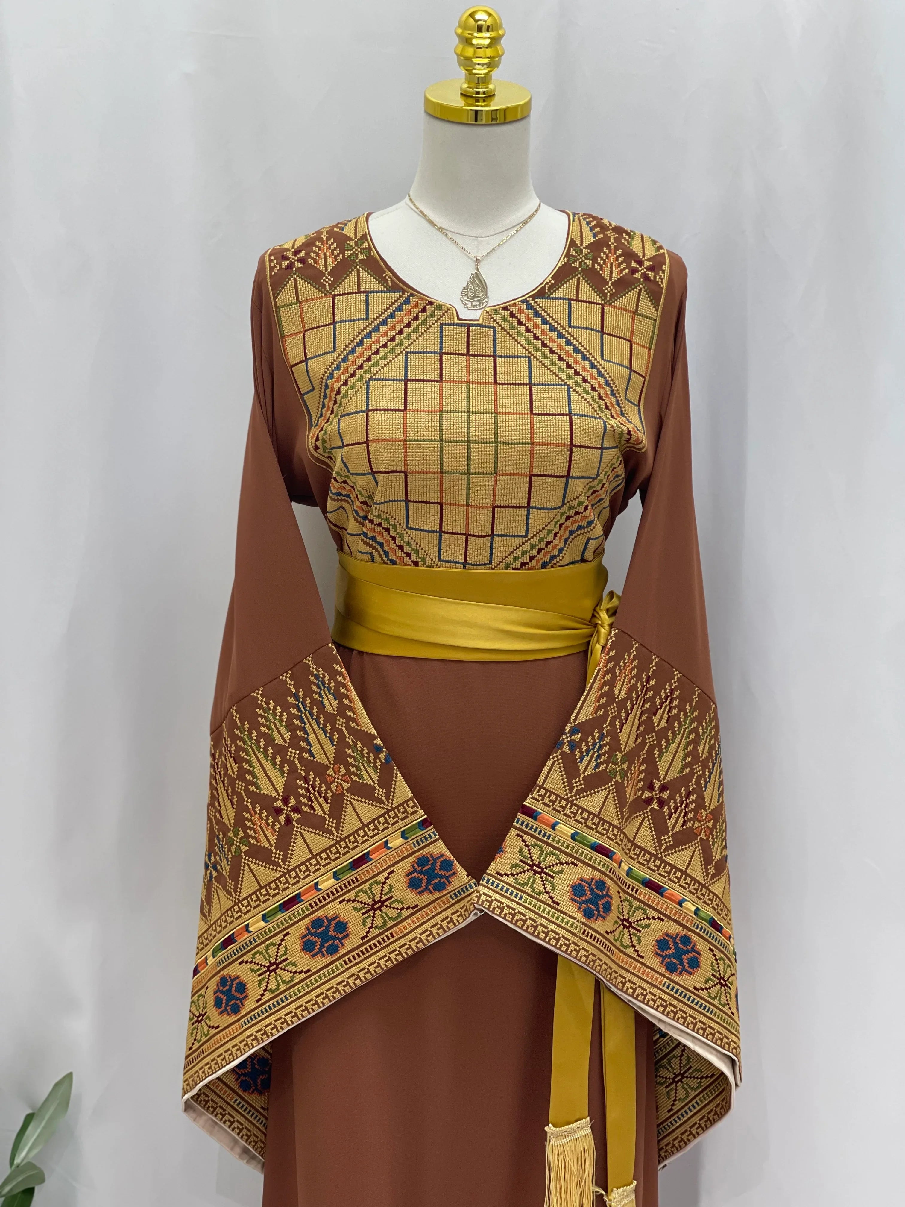 Embroidered Palestinian thoub dress with intricate geometric patterns and yellow sash by Palestinian Elegance