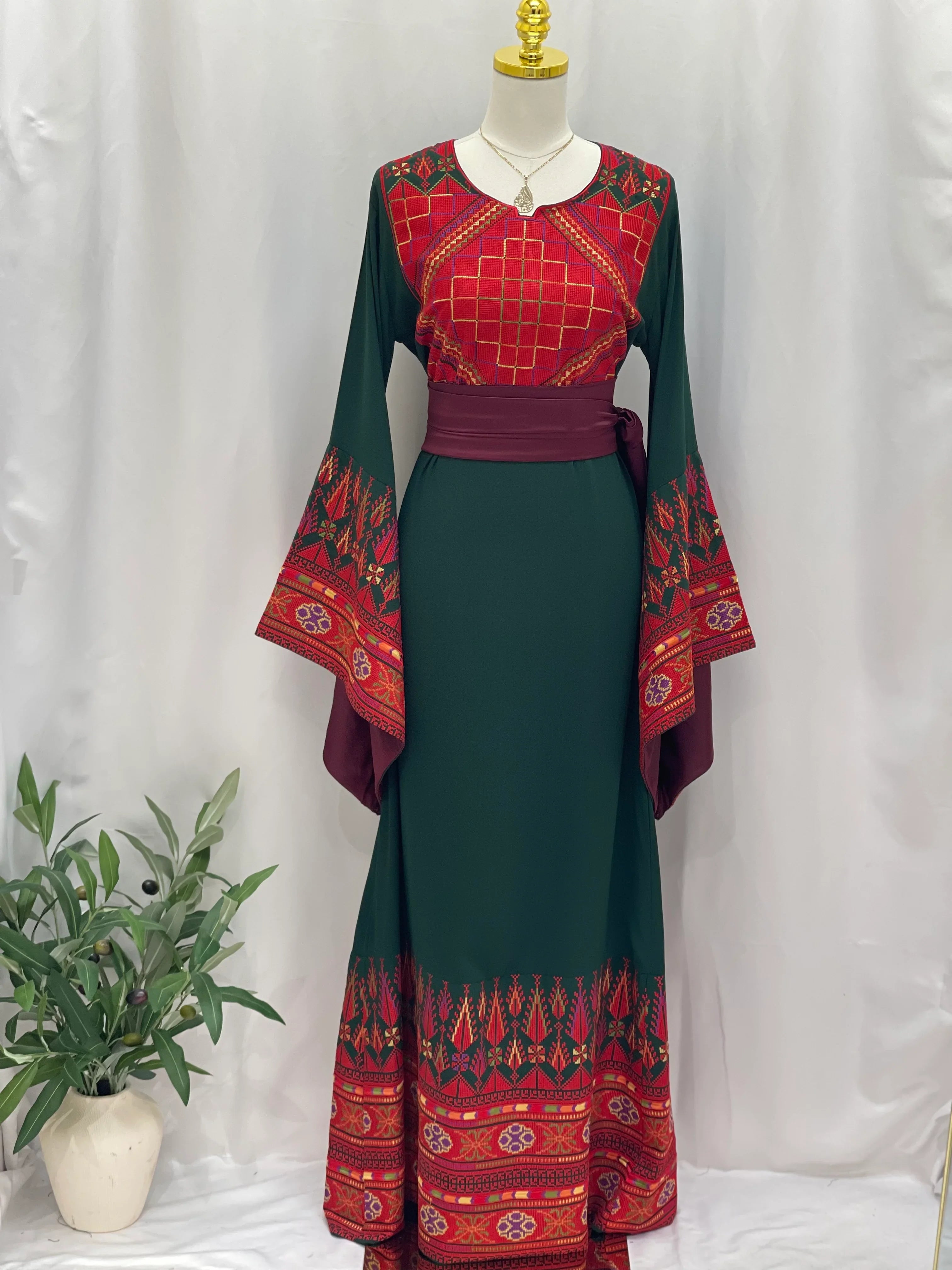 Embroidered Palestinian thoub dress in green with red traditional patterns and wide sleeves by Palestinian Elegance