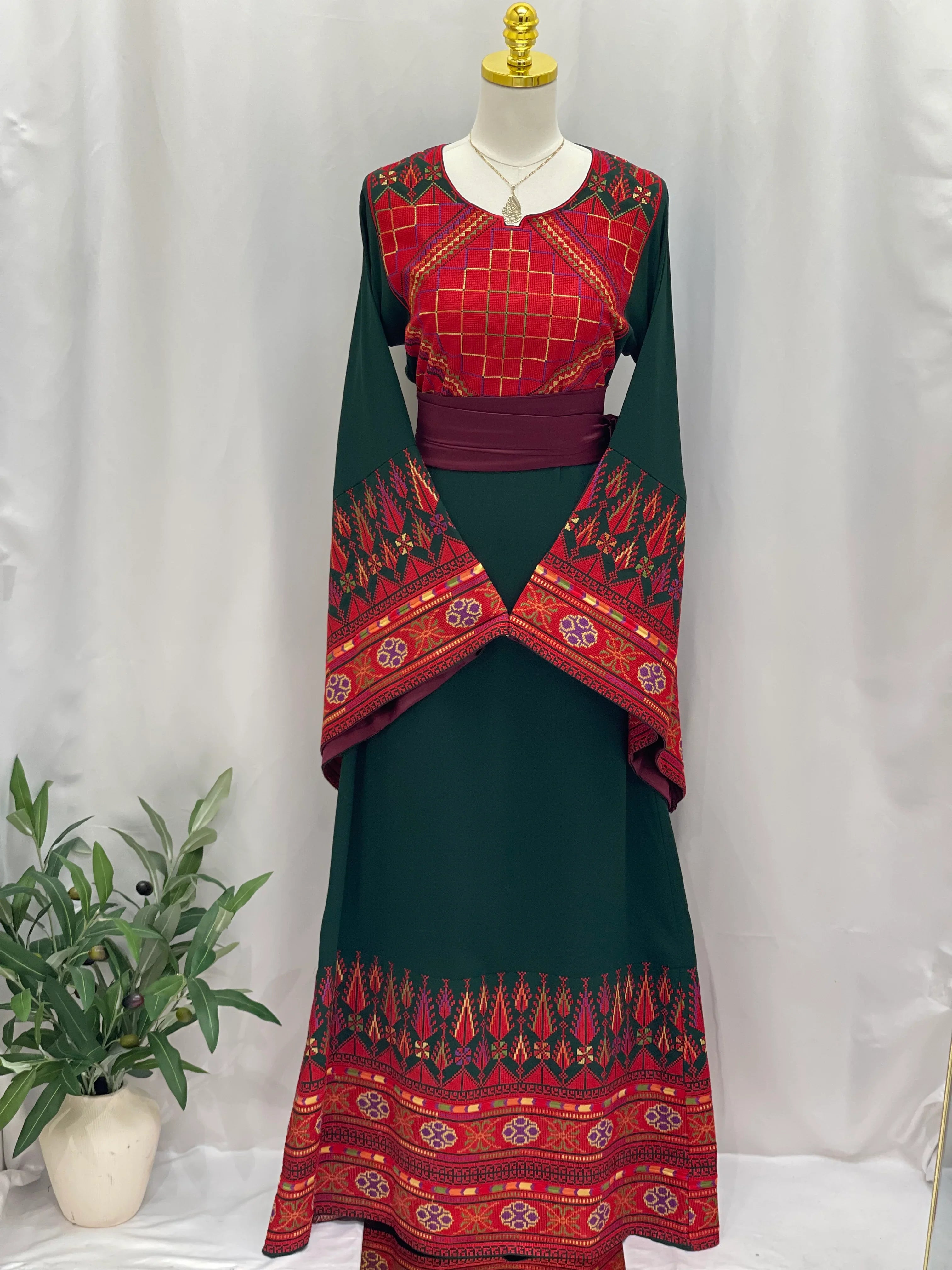 Embroidered Palestinian thoub dress by Palestinian Elegance in green and red with traditional patterns and wide sleeves