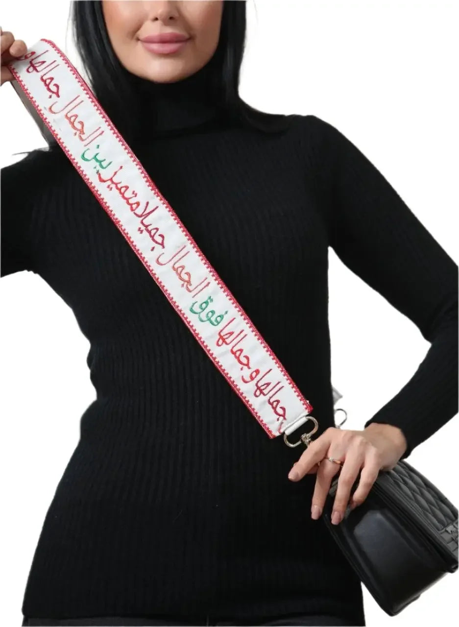 Embroidered purse with poetic strap featuring Arabic calligraphy held by woman in black sweater
