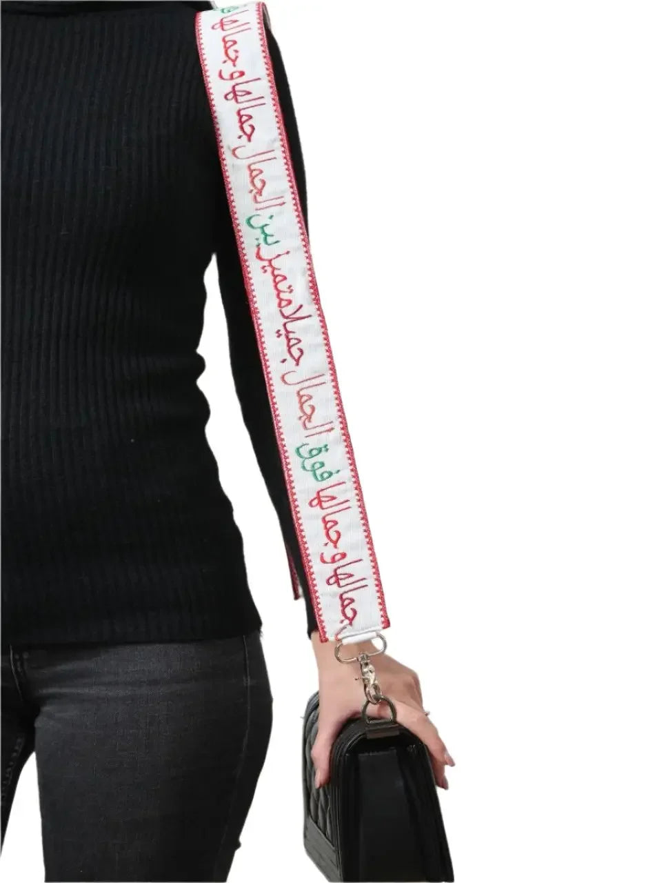 Black purse with embroidered purse with poetic strap featuring red and green Arabic calligraphy