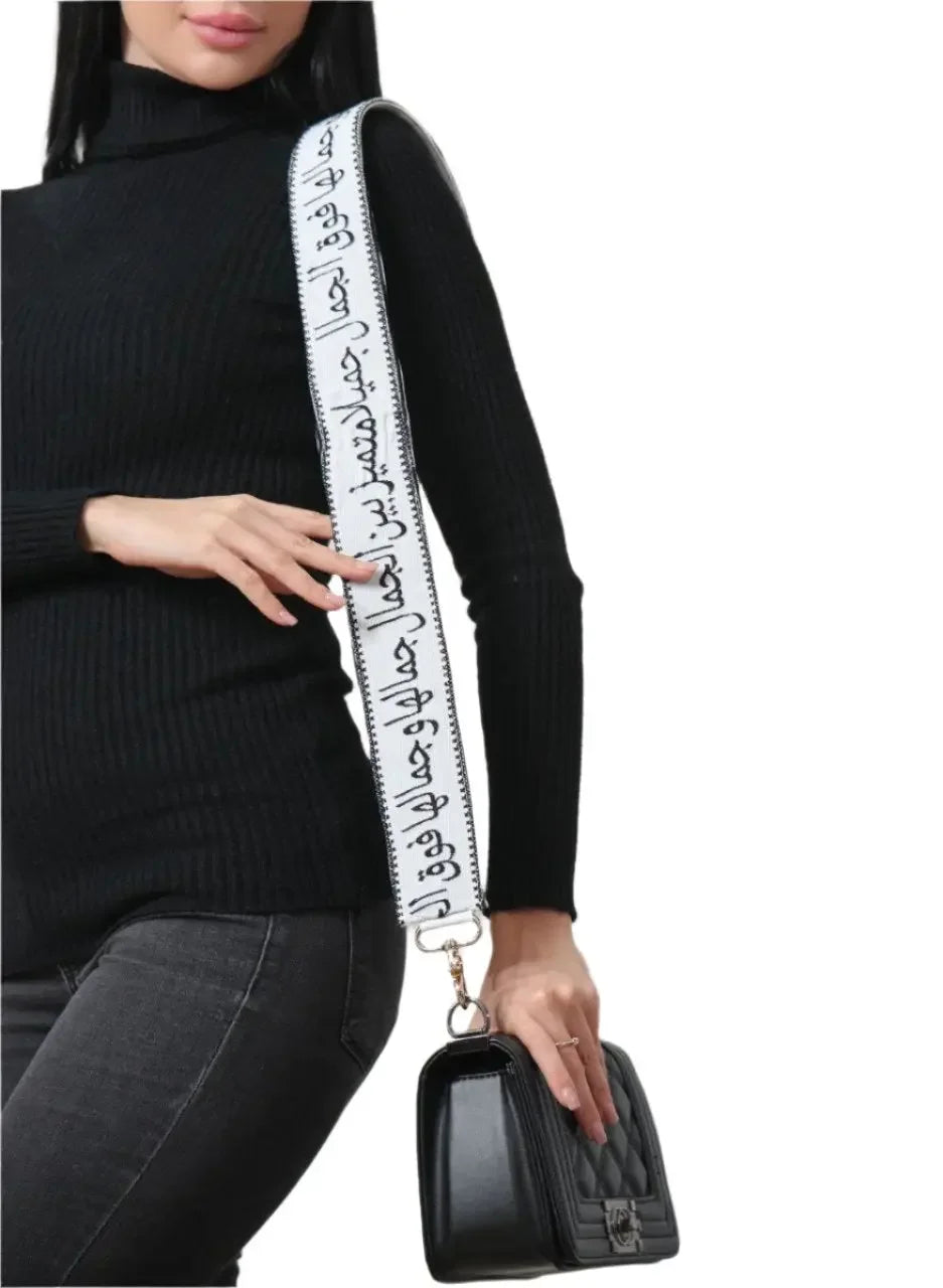 Palestinian Elegance black handbag featuring an embroidered purse with poetic strap worn by a woman in a black sweater