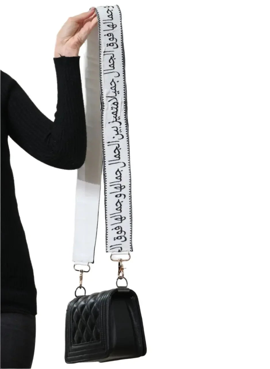 Black quilted purse with embroidered purse with poetic strap held by a person in black outfit