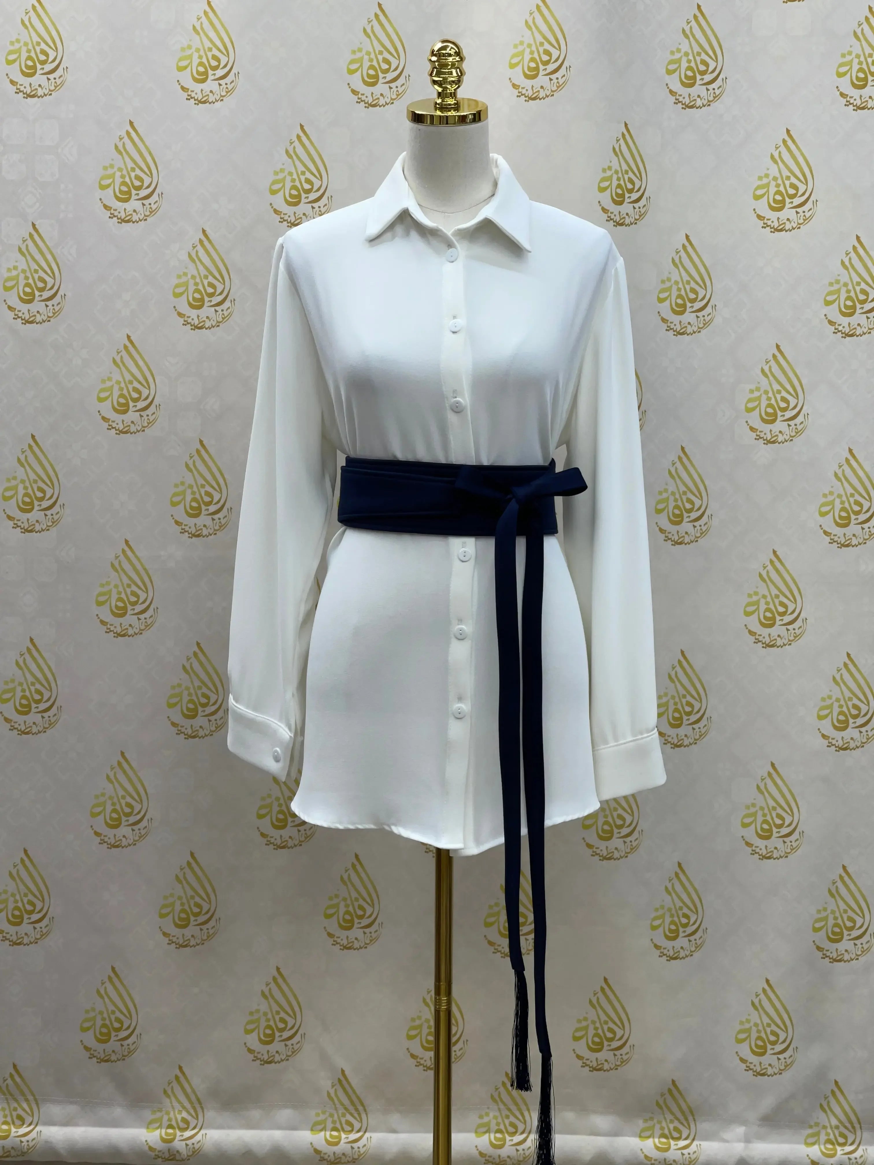 White button-down shirt styled with a navy embroidered satin belt tied around the waist