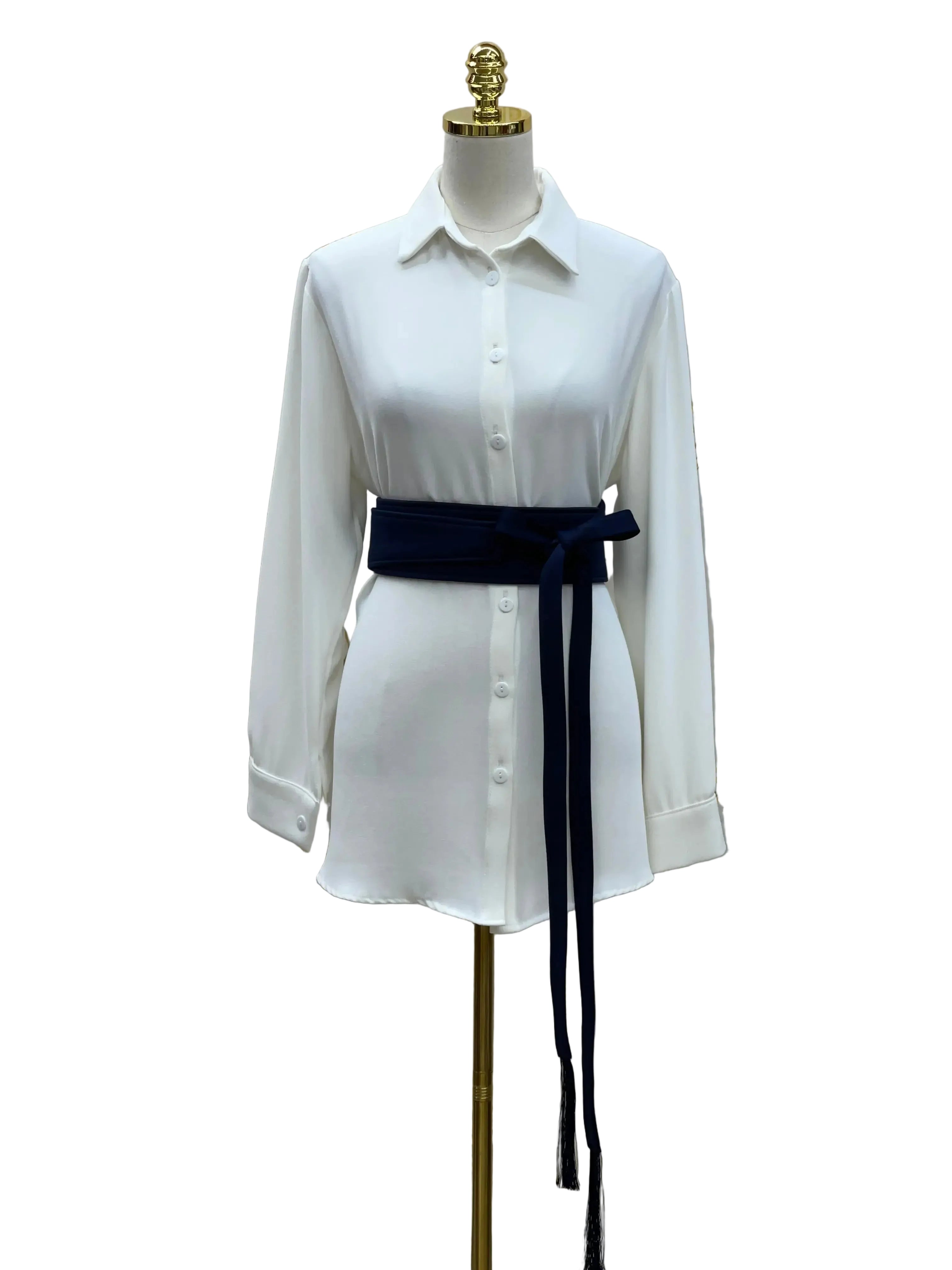 White button-down shirt styled with a navy embroidered satin belt tied around the waist