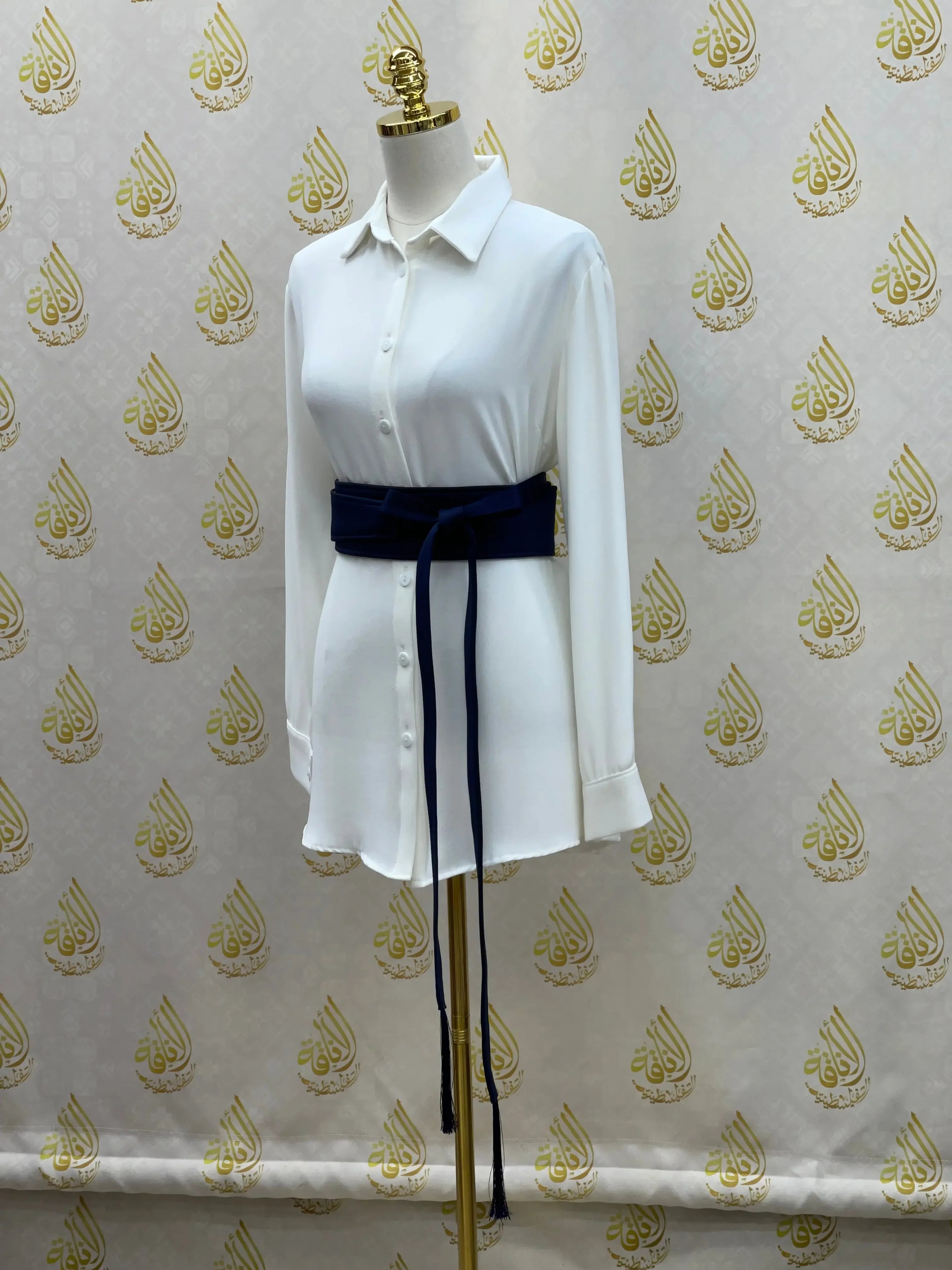 Palestinian Elegance embroidered satin belt in navy blue worn over white long sleeve shirt on mannequin