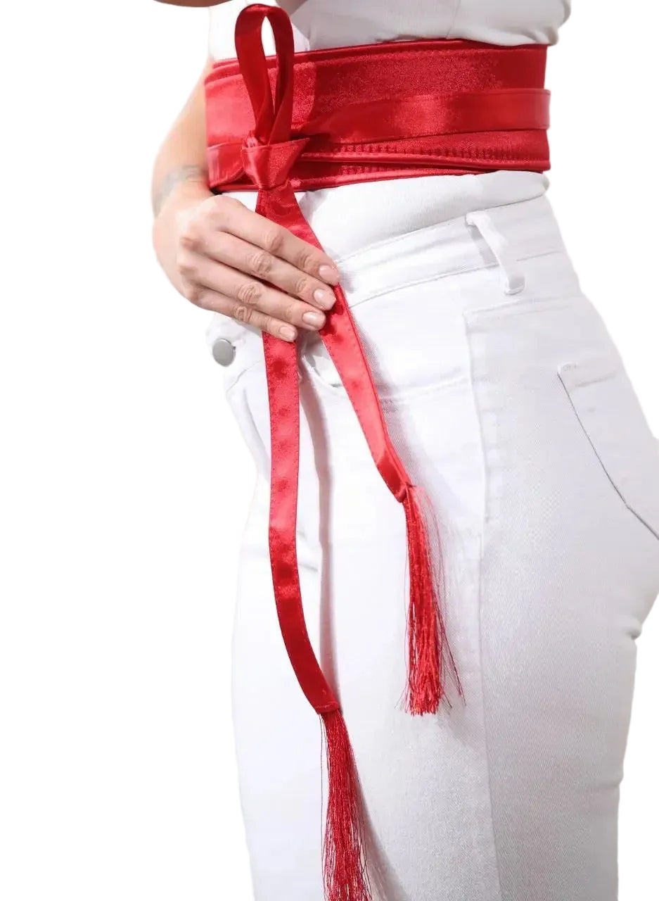 Red embroidered satin belt tied around waist over white pants by Palestinian Elegance