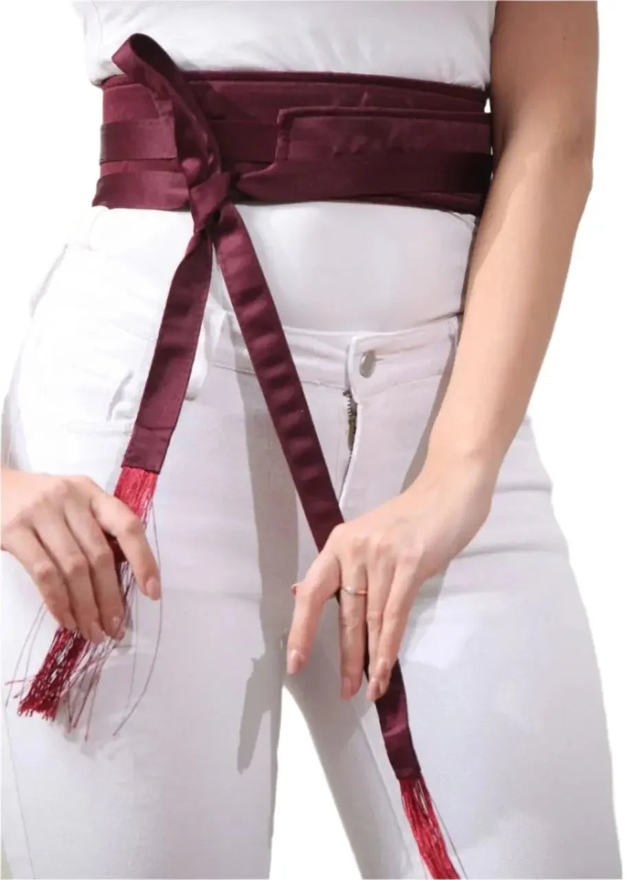 Embroidered satin belt in deep burgundy wrapped around waist with tassel ends from Palestinian Elegance