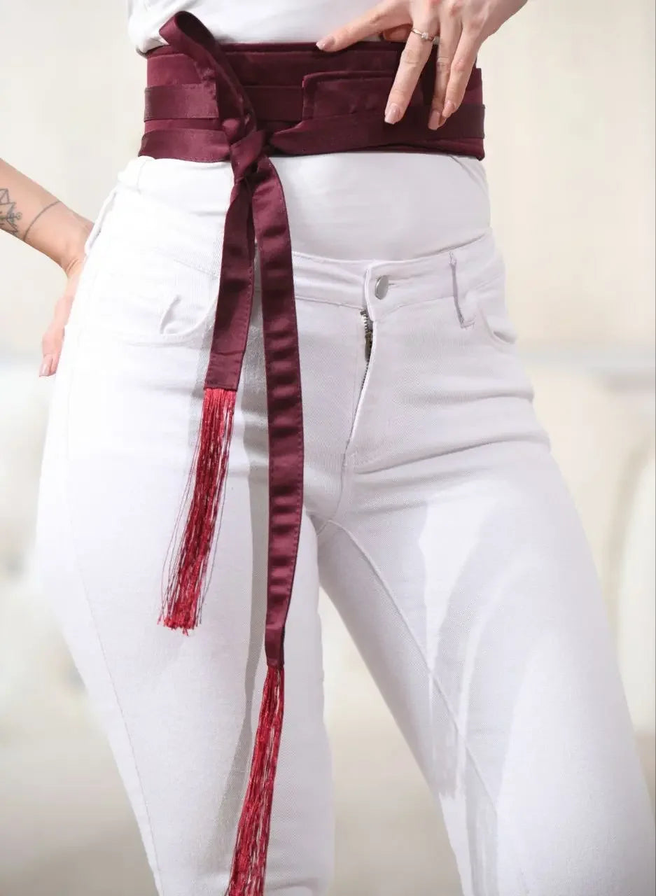 Palestinian Elegance embroidered satin belt in deep burgundy wrapped around waist with tassel ends