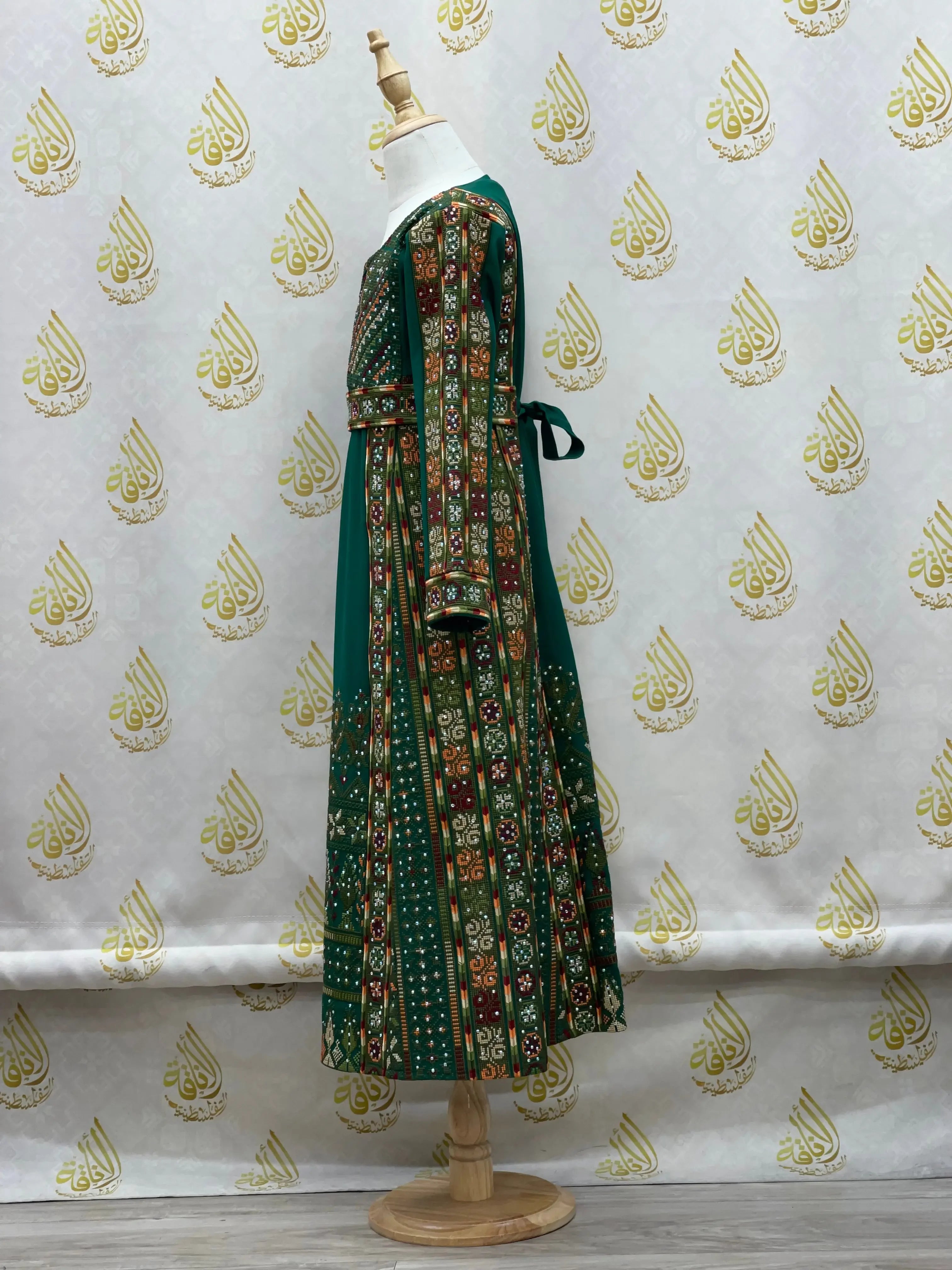 Palestinian Elegance embroidered thoub for girls in green with detailed traditional embroidery on a mannequin