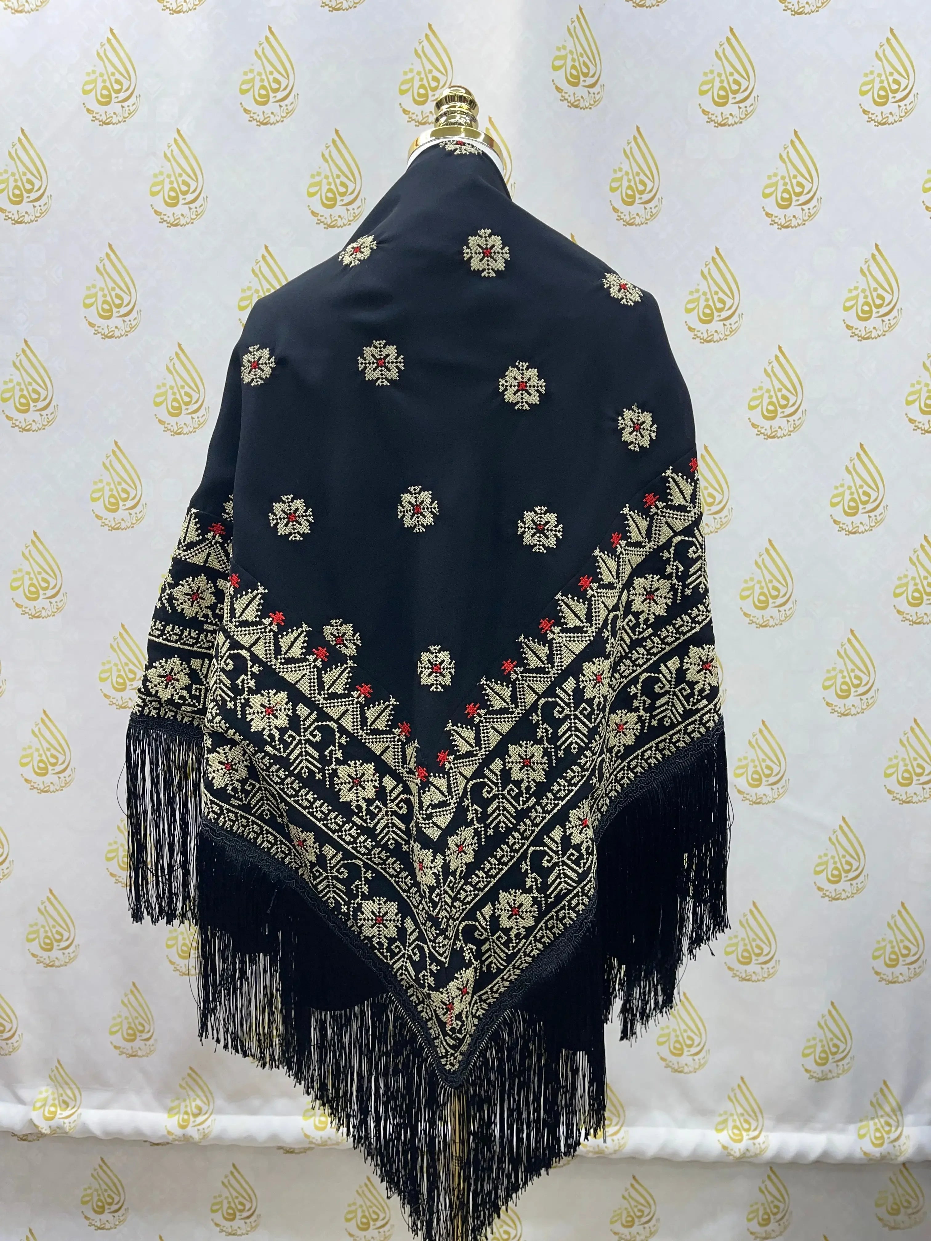 Black embroidered triangle shawl with intricate cream and red floral patterns and fringe from Palestinian Elegance