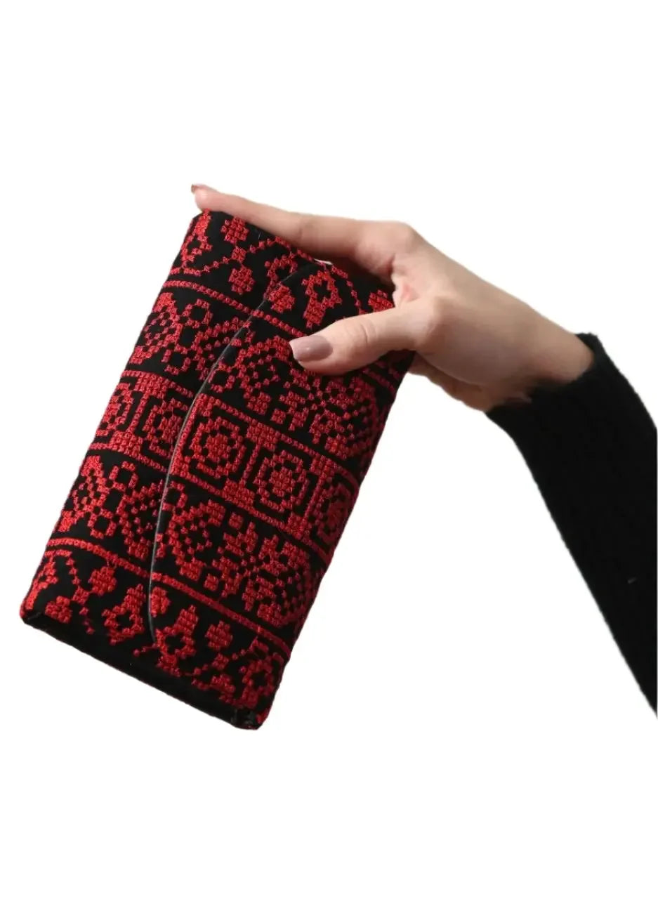 Hand holding Palestinian Elegance embroidered wallet for women in black and red traditional design