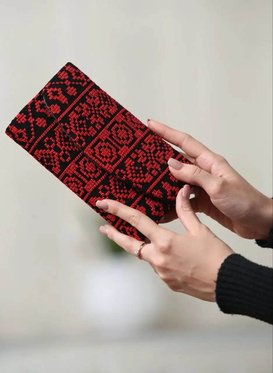 Palestinian Elegance embroidered wallet for women in black and red traditional design held by hands