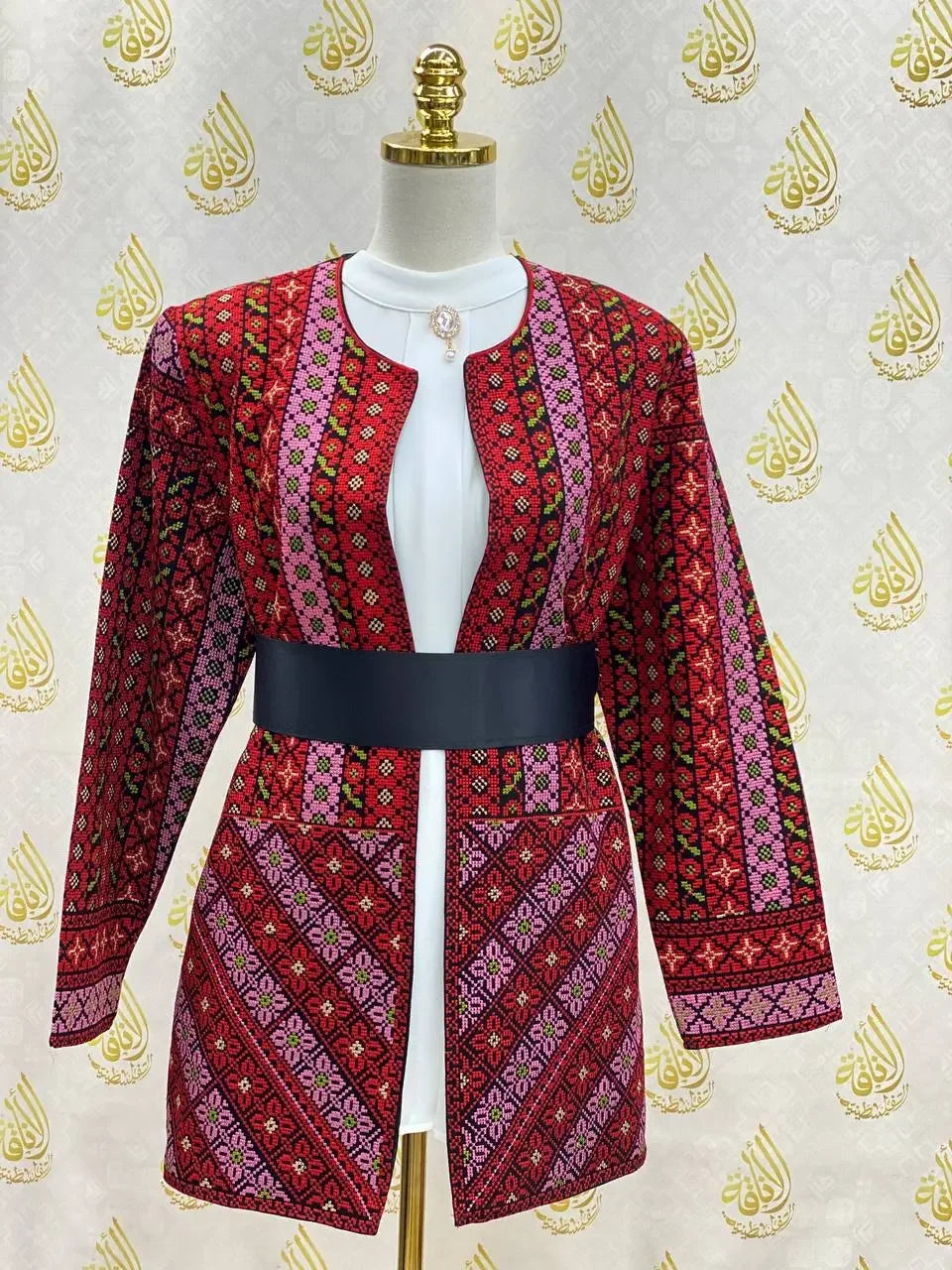 Palestinian Elegance embroidered women's jacket with detailed red and pink geometric patterns and black belt