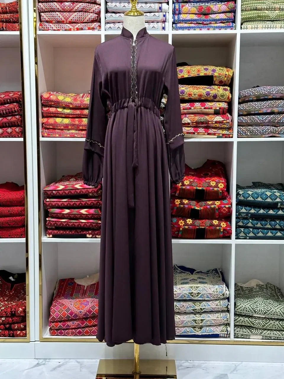 Palestinian Elegance purple fancy abaya dress for women displayed on mannequin with traditional fabric background