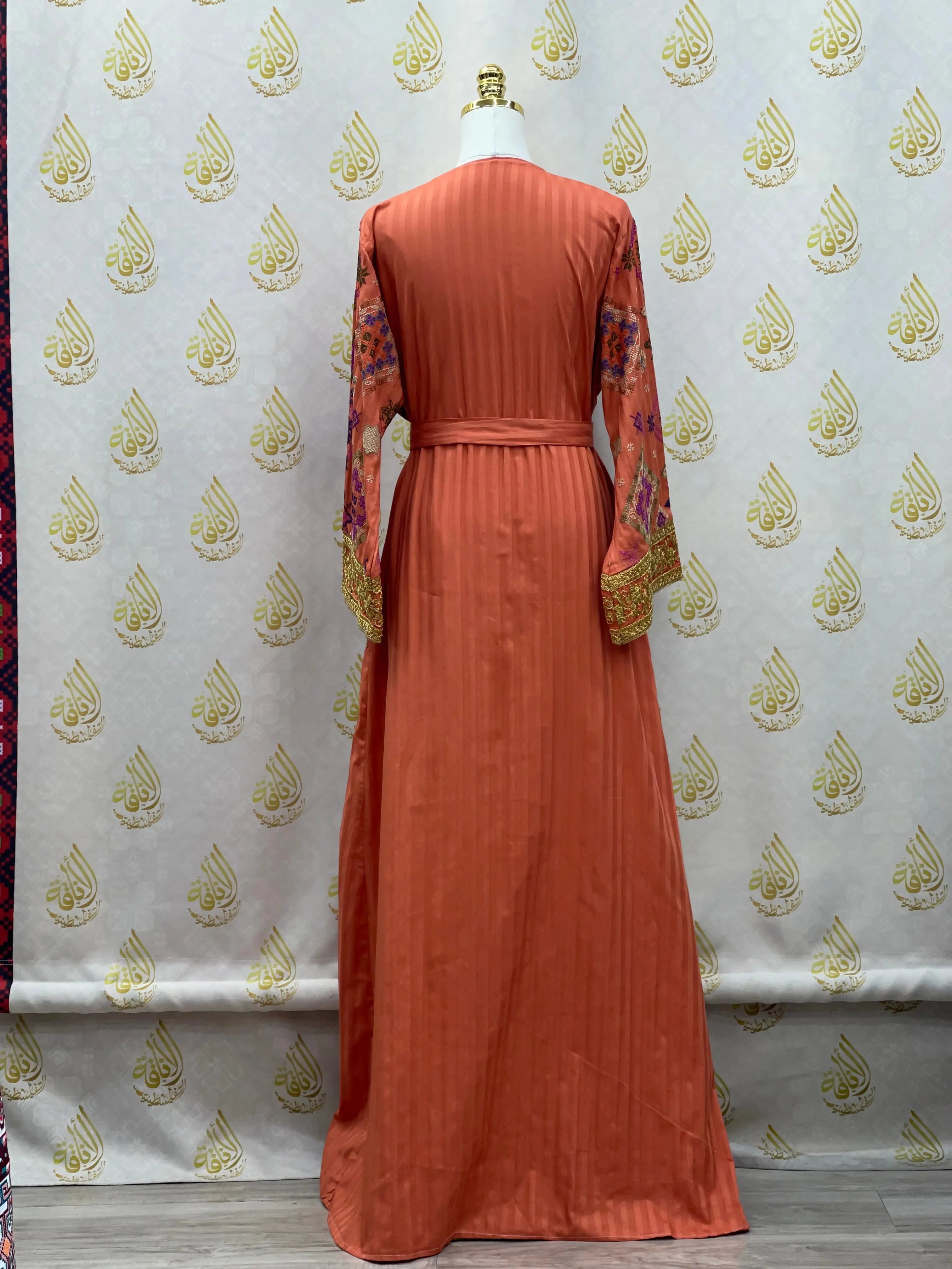Back view of Gabani embroidered long cardigan in rust orange with floral sleeves and belted waist by Palestinian Elegance