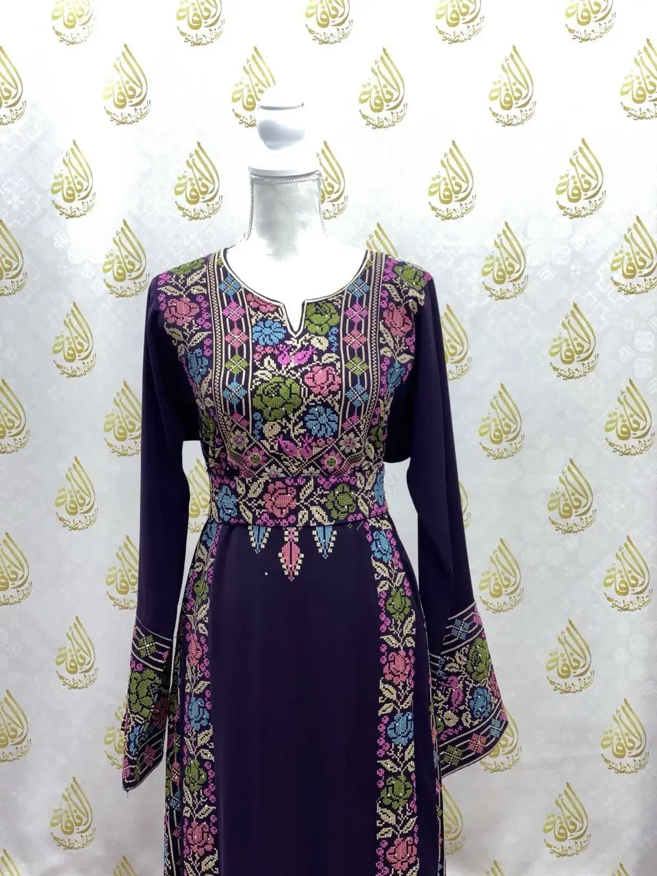 Palestinian Elegance hand-embroidered abaya in dark fabric featuring colorful floral embroidery on bodice and sleeves