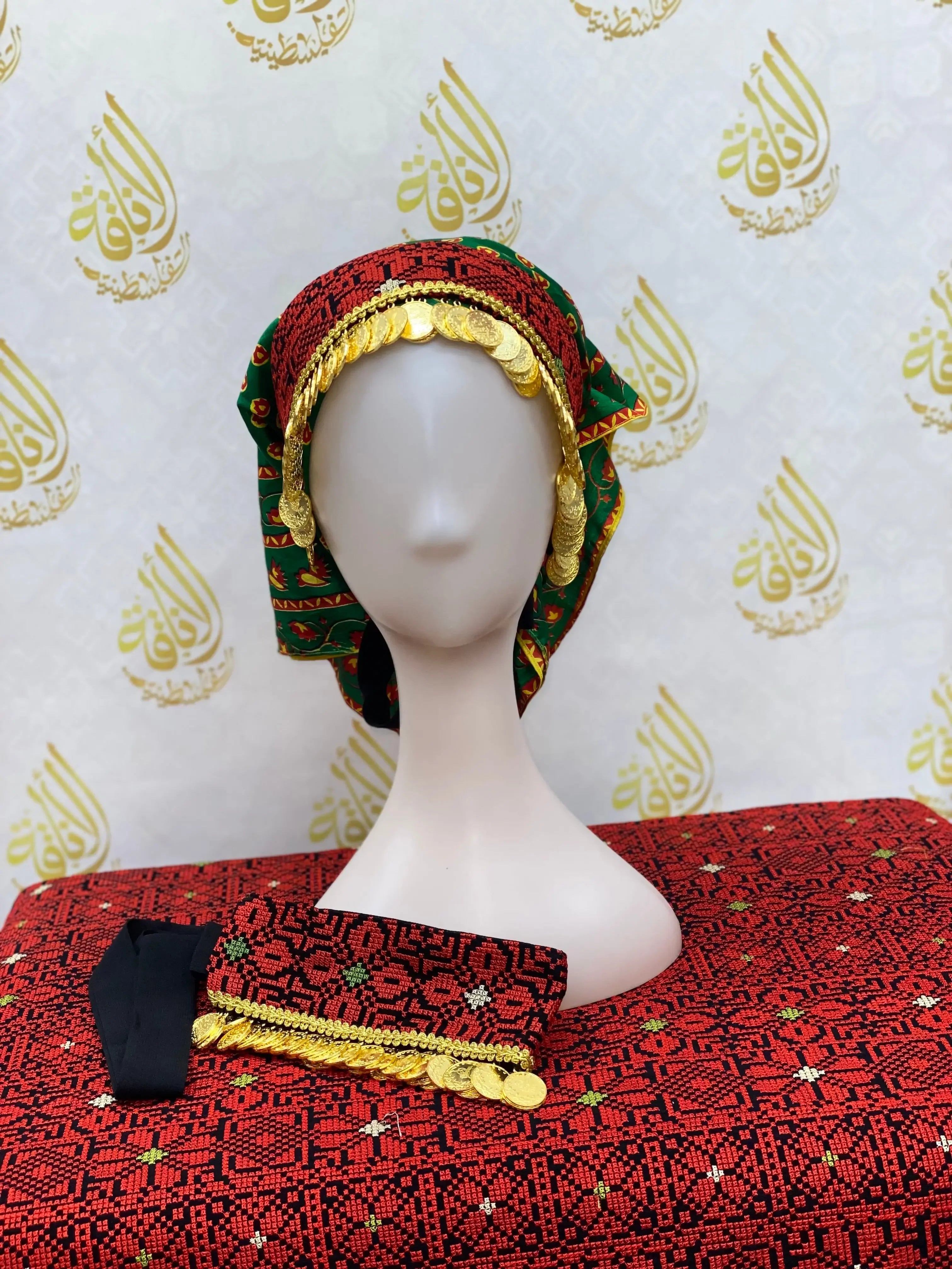 Hand embroidered tatreez headscarf with intricate red and green patterns displayed on a mannequin