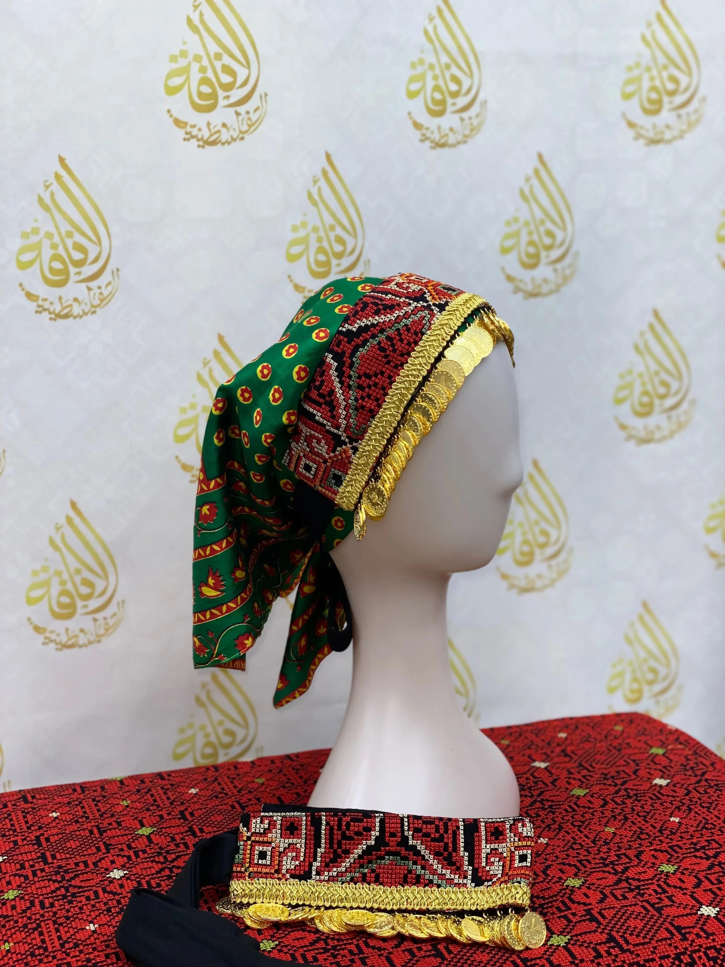Hand embroidered tatreez headscarf in green and red with gold accents displayed on a mannequin by Palestinian Elegance