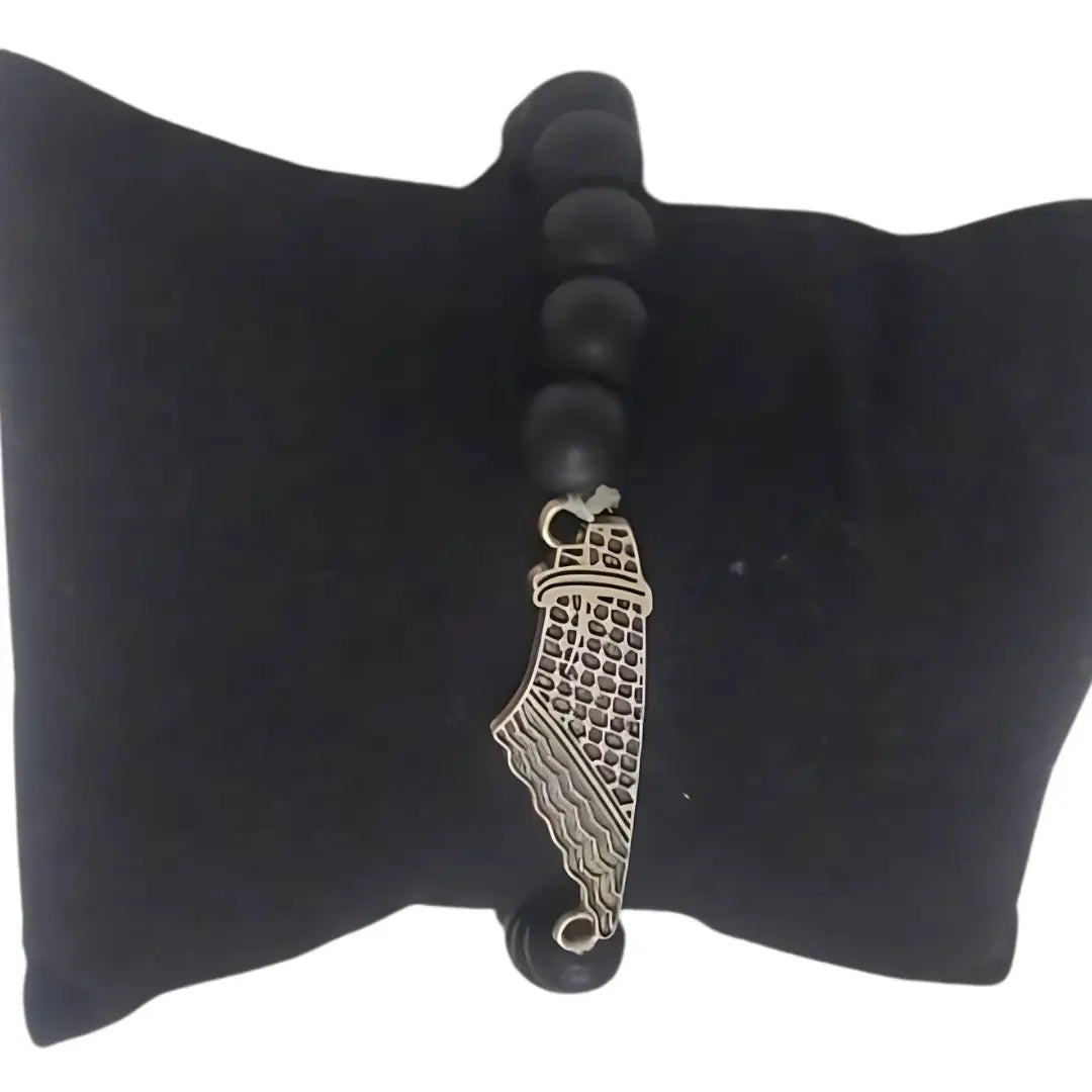 Palestinian Elegance handcrafted kuffiyeh bracelet with black beads and silver wing charm on black cushion