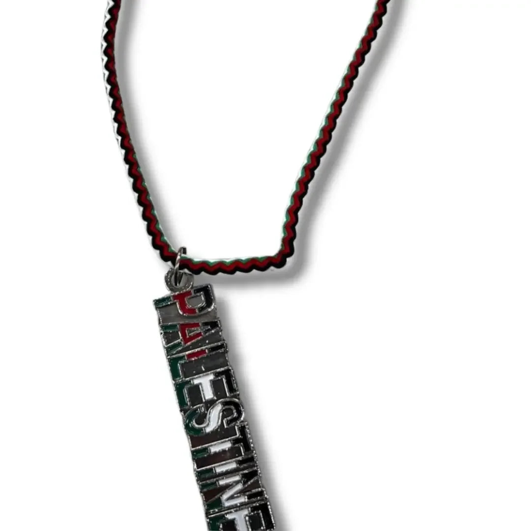 Handmade Palestinian silver necklace with a pendant spelling Palestine and a red, black, and green cord