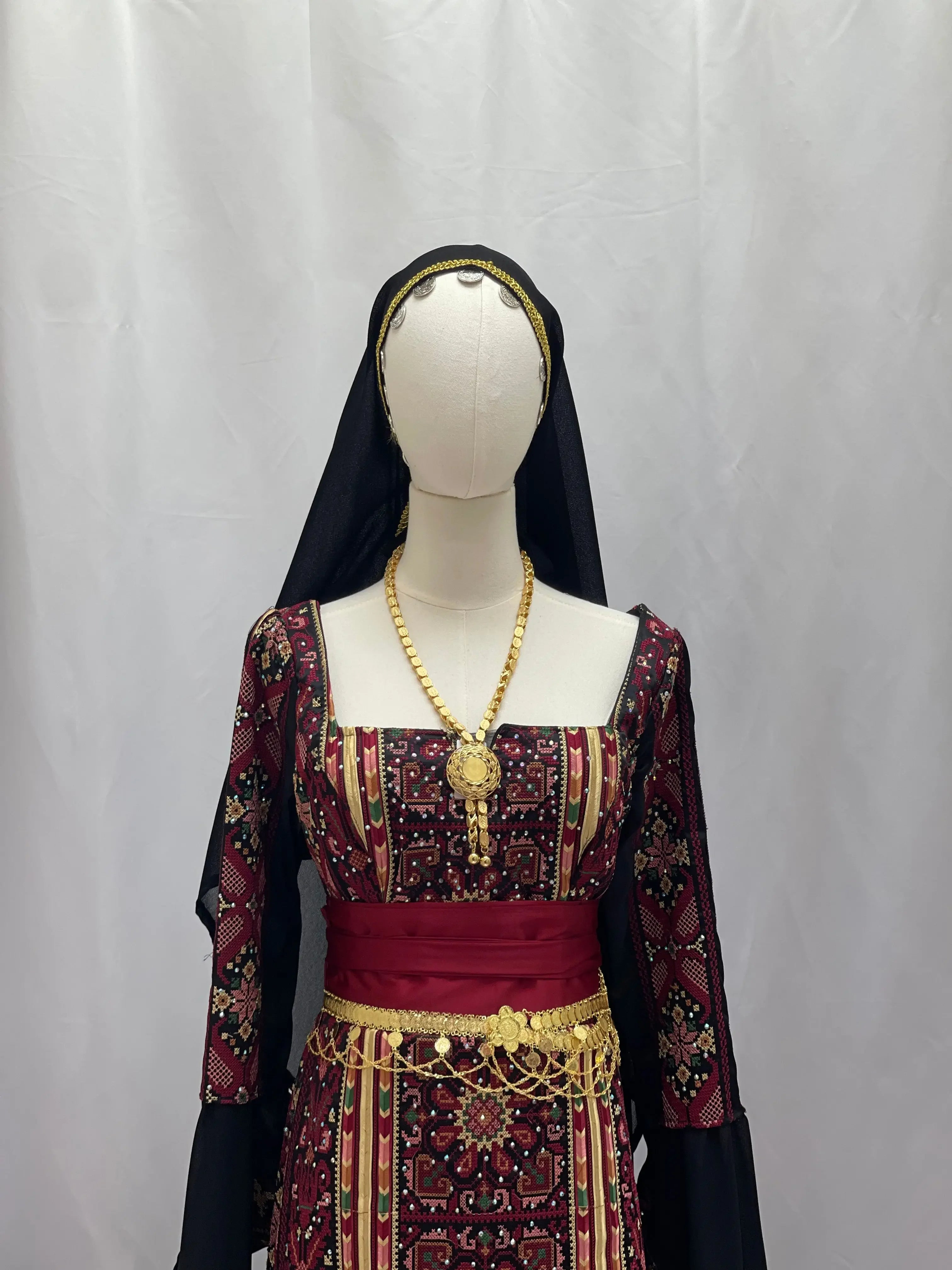 Traditional khirka with gold coins worn over embroidered Palestinian dress with headscarf accessory