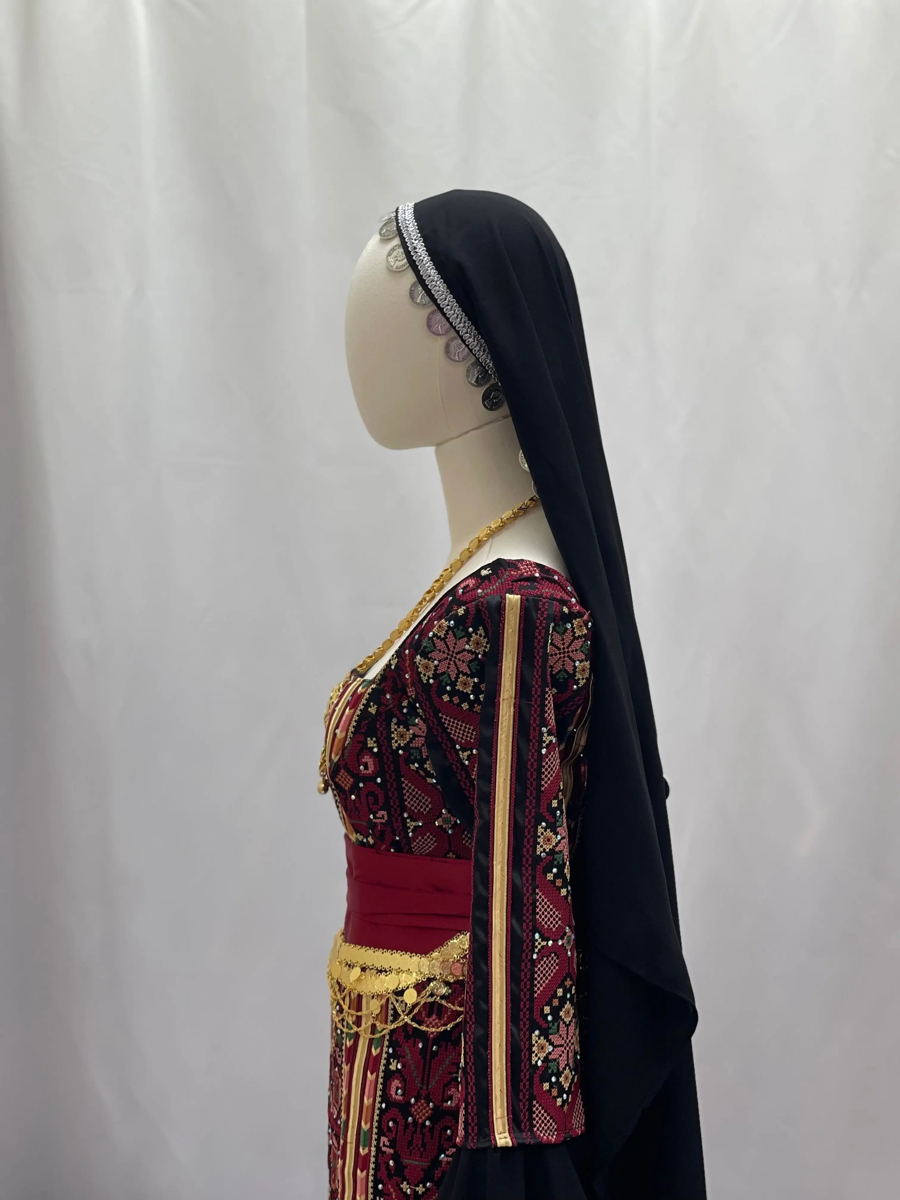 Side view of traditional khirka with gold coins worn over a patterned dress and black head covering